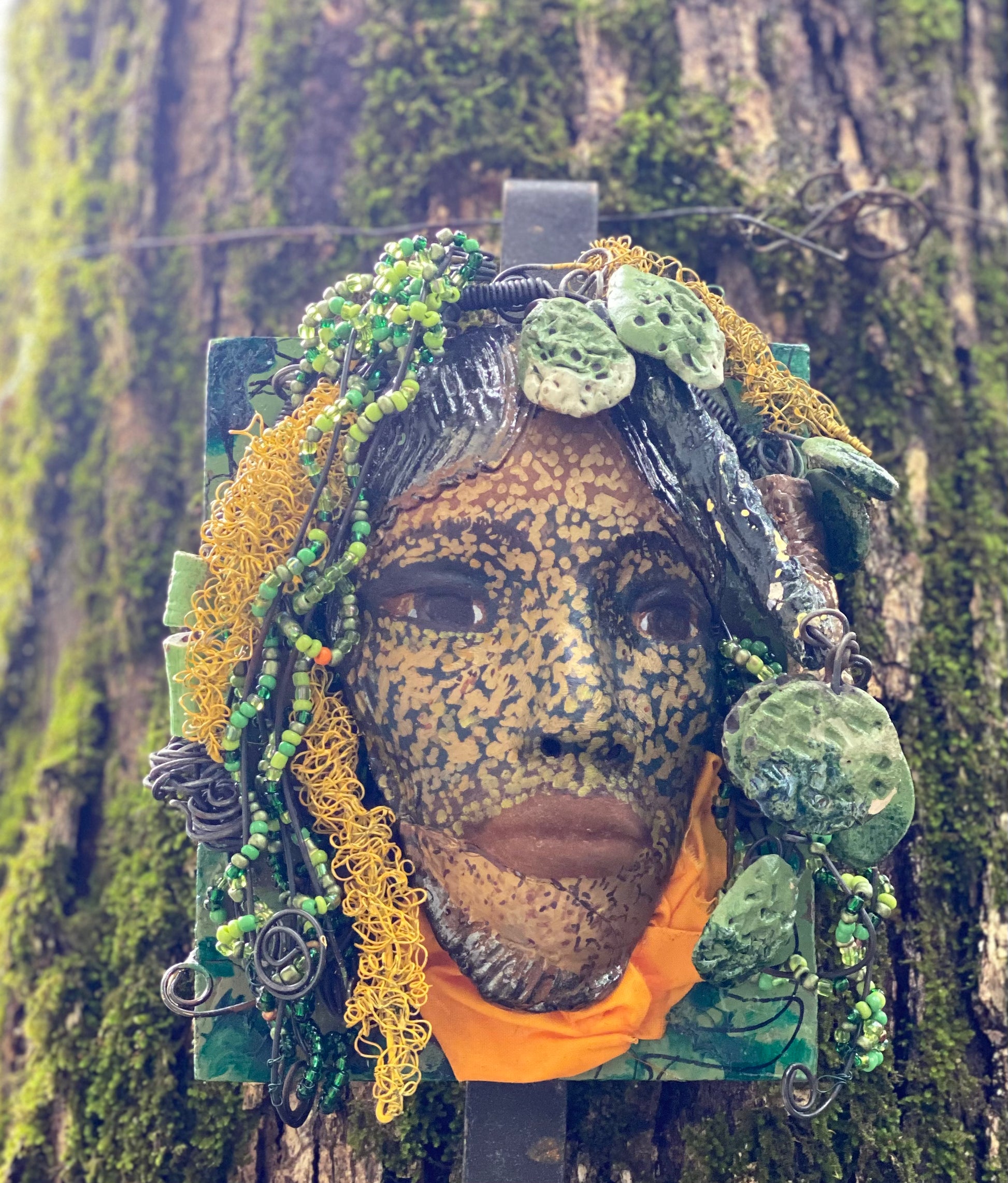 Casey is one of a new 2022  series of tribal masks that are mounted on wood. I started making art soon after seeing authentic African artwork at the Smithsonian Museum of African Art. I was in total awe. Casey is 6” x 7 x 1 and weighs 1.13 lbs.  She has a contagious smile. Casey's face is speckled gold. 12 handmade raku fired beads Over 60 mini 6mm multi colored beads  Over 60 feet of 16 and 24 gauge twisted wire for hair! Over two weeks to complete! Casey is ready to be mounted inside or outdoors!
