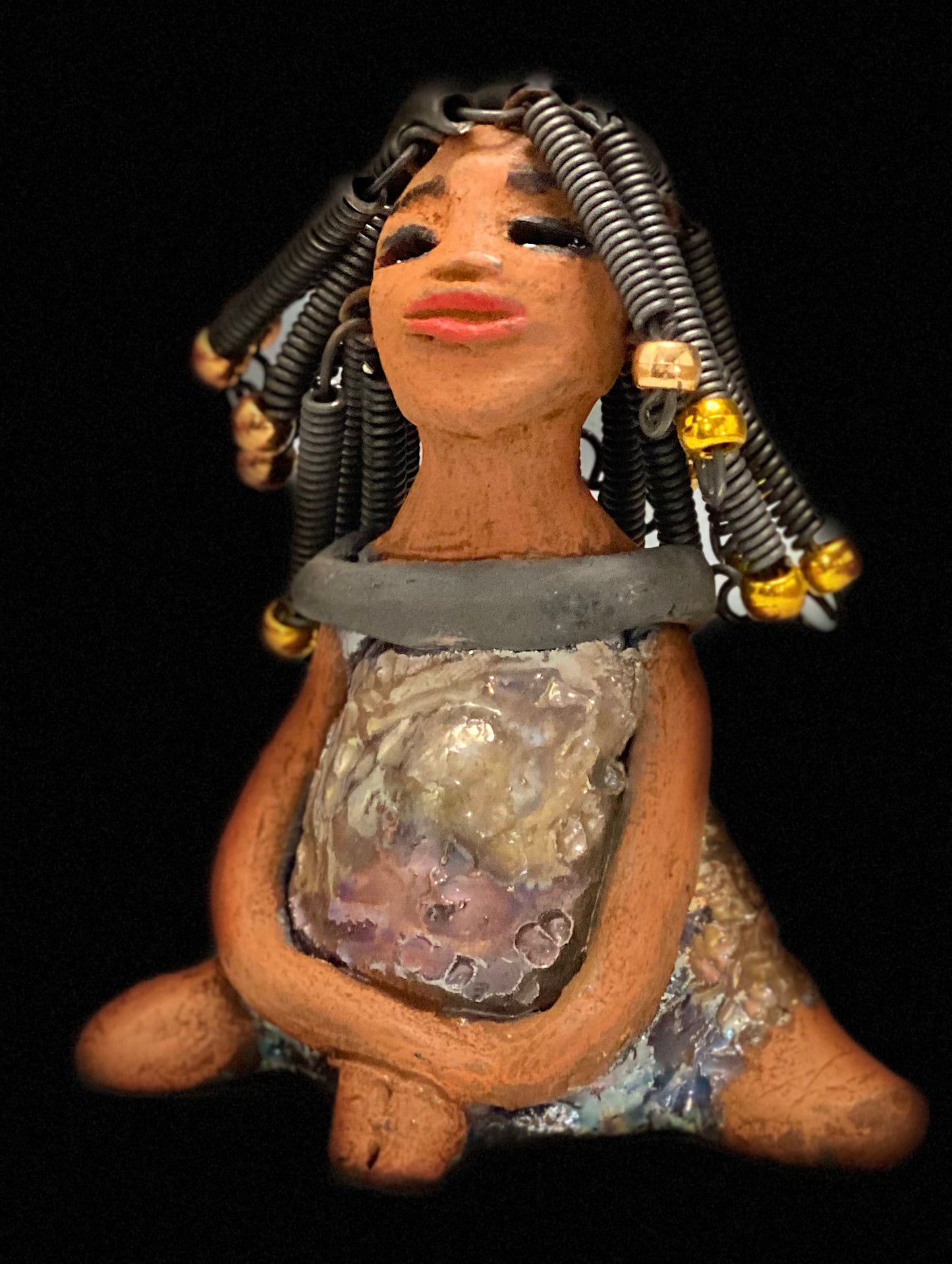Meet Sadie Sadie stands 5.5" x 4" x 3" and weighs 8.7 ozs. She wears a lovely glossy metallic gold dress.. Sadie has over15 feet of coiled wire hair. Sadie appears to sit in a yoga pose. Her long arms rest at her side. Sadie is a great starter piece from the Herdew Collection!