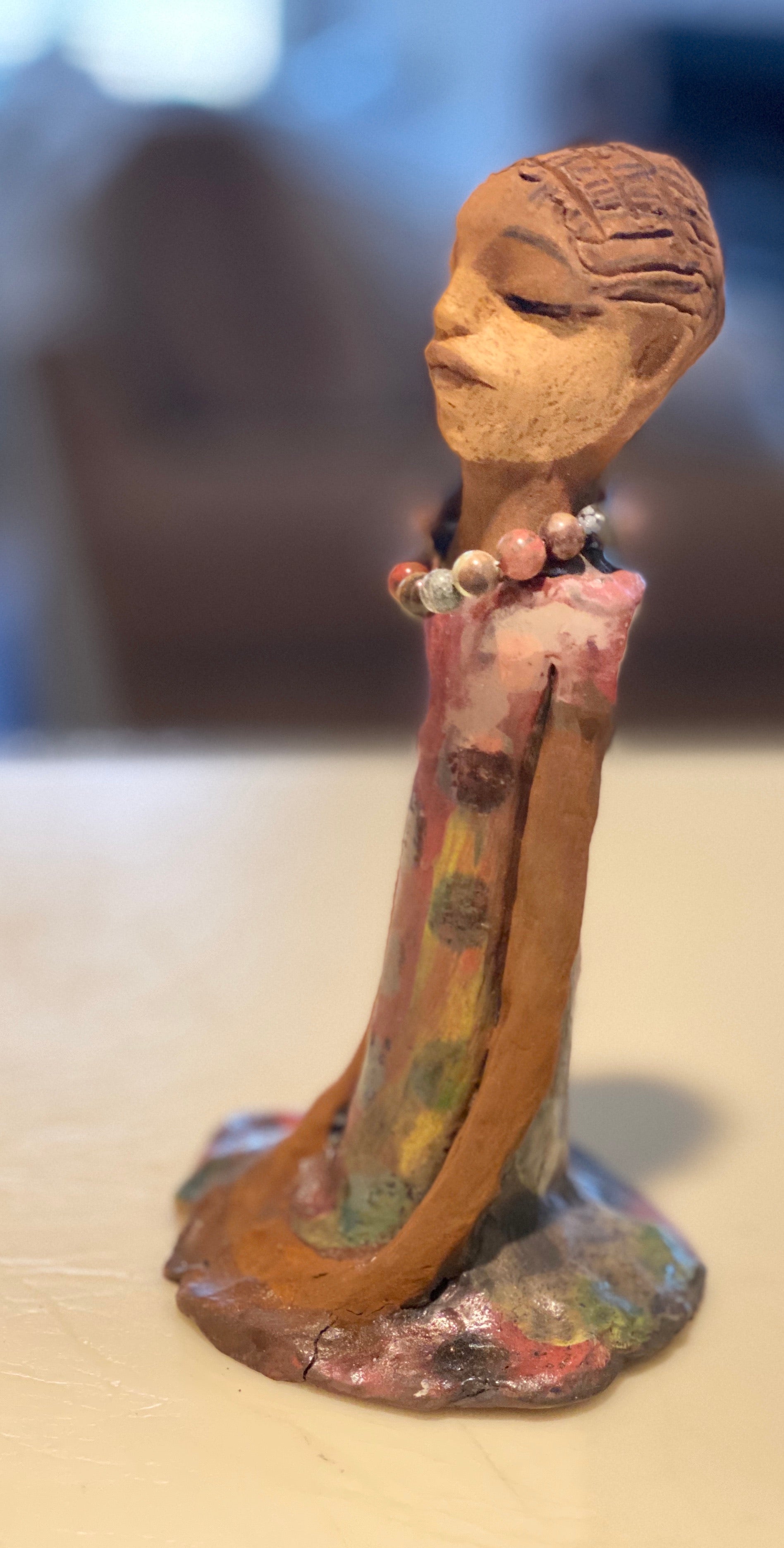 Mena long loving arms rest beside her multicolored copper green dress. Mena is a sophisticated lady that will grace your home.