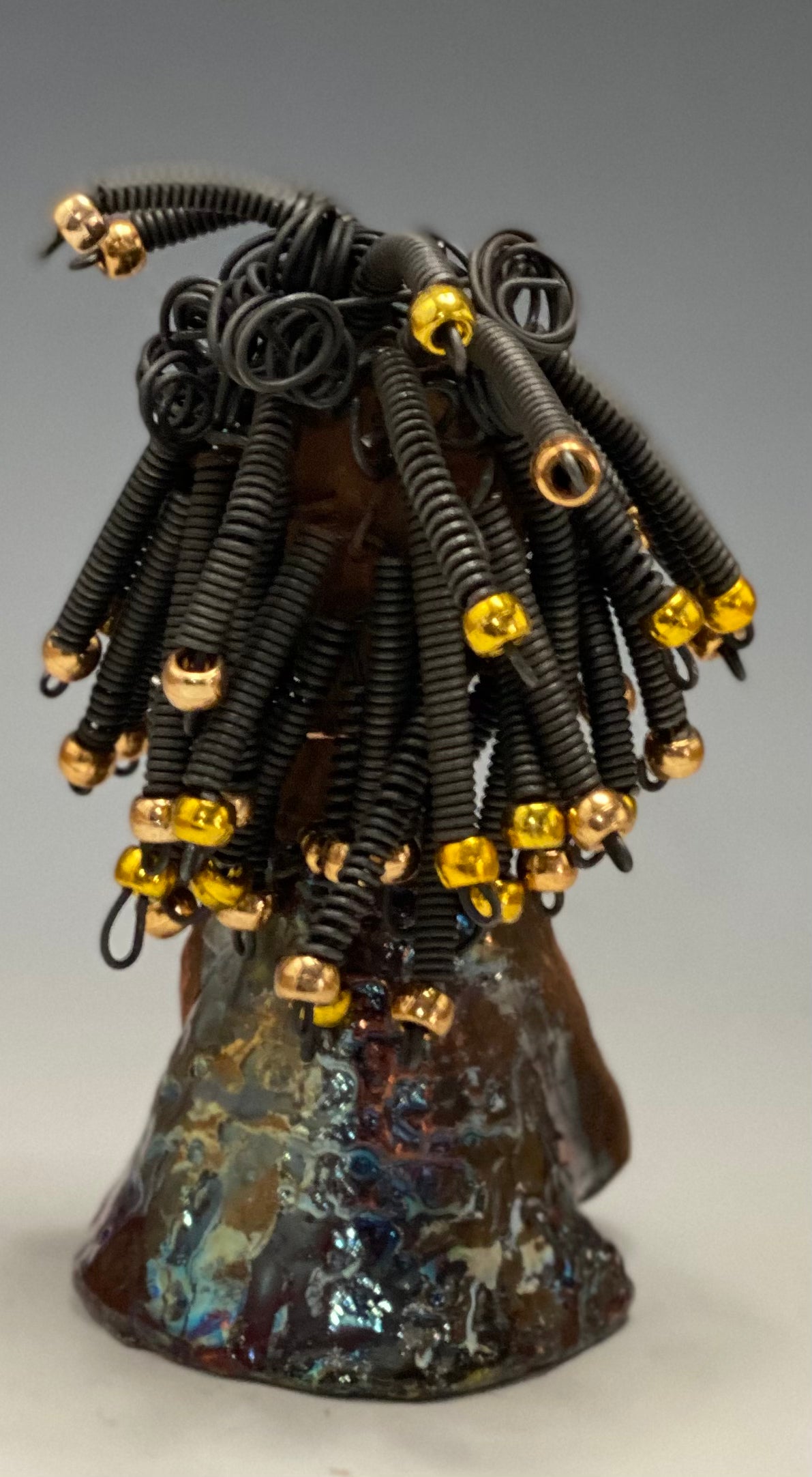 Meet Alexus Alexus stands 7.5" x 4" x 4" and weighs 1.05 lbs. She wears a lovely glossy metallic gold dress adorn by a spiral copper necklace. Alexus has over15 feet of coiled wire hair with gold beads.. Alexus appears to sit in a yoga pose. Her long arms rest at her side. Alexus is a great starter piece from the Herdew Collection!