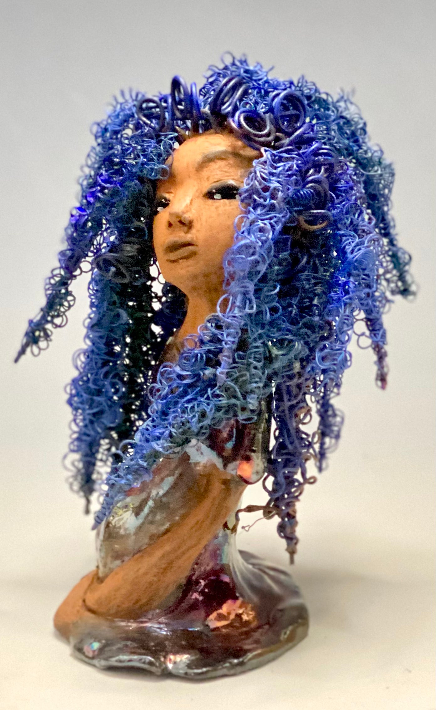 Rachel Rachel stands 8" x 6" x 5.5" and weighs 1.9 lbs. She has a lovely honey brown complexion with cocoa brown lips. She has long twisted wire locs hairstyle waist down! Rachel has a very colorful metallic copper blue antique glazed dress. She has over 75 feet of 16 and 24 gauge wire for hair. It took over 6 hours just to do her hair! With eyes wide opened, Rachel has hope of finding a new home.