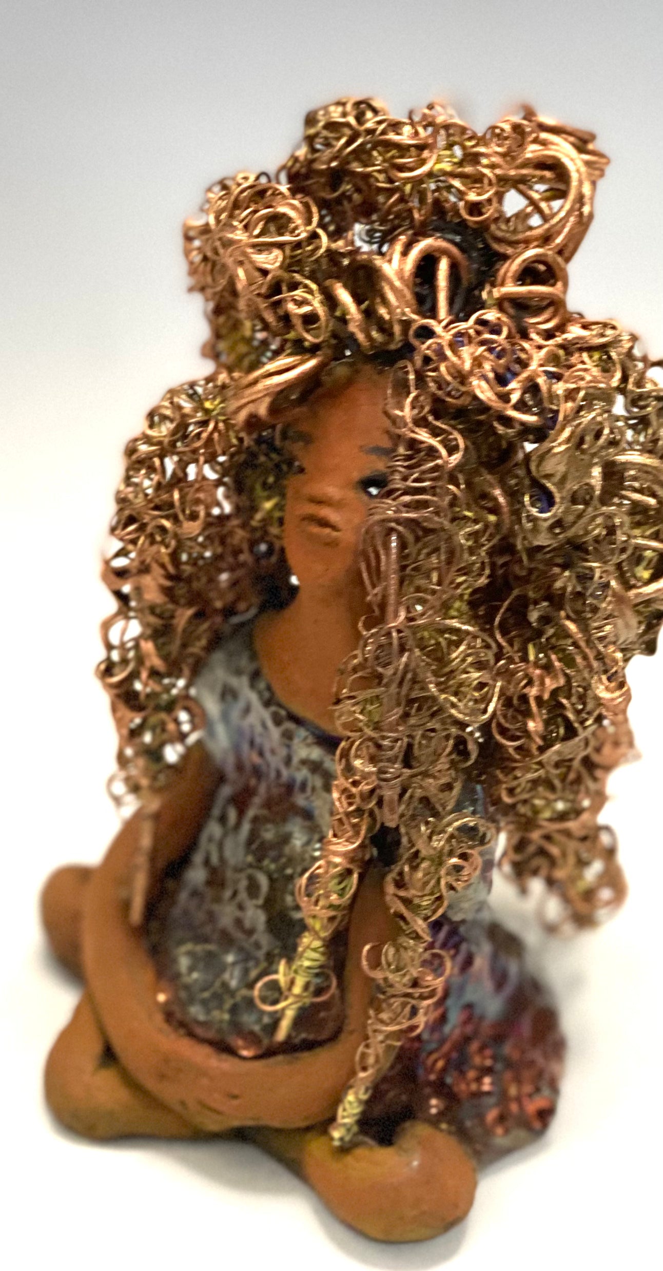 Meet Tiana! Tiana stands 5" x 3.5" x 3.5" and weighs 10 ozs. She has a lovely honey brown complexion. Tiana's dress is metallic copper. She has her long loving arms resting at her side. " I am really pleased with Tiana's blue beaded necklace and her new wire hair Find a place in your space for Tiana!