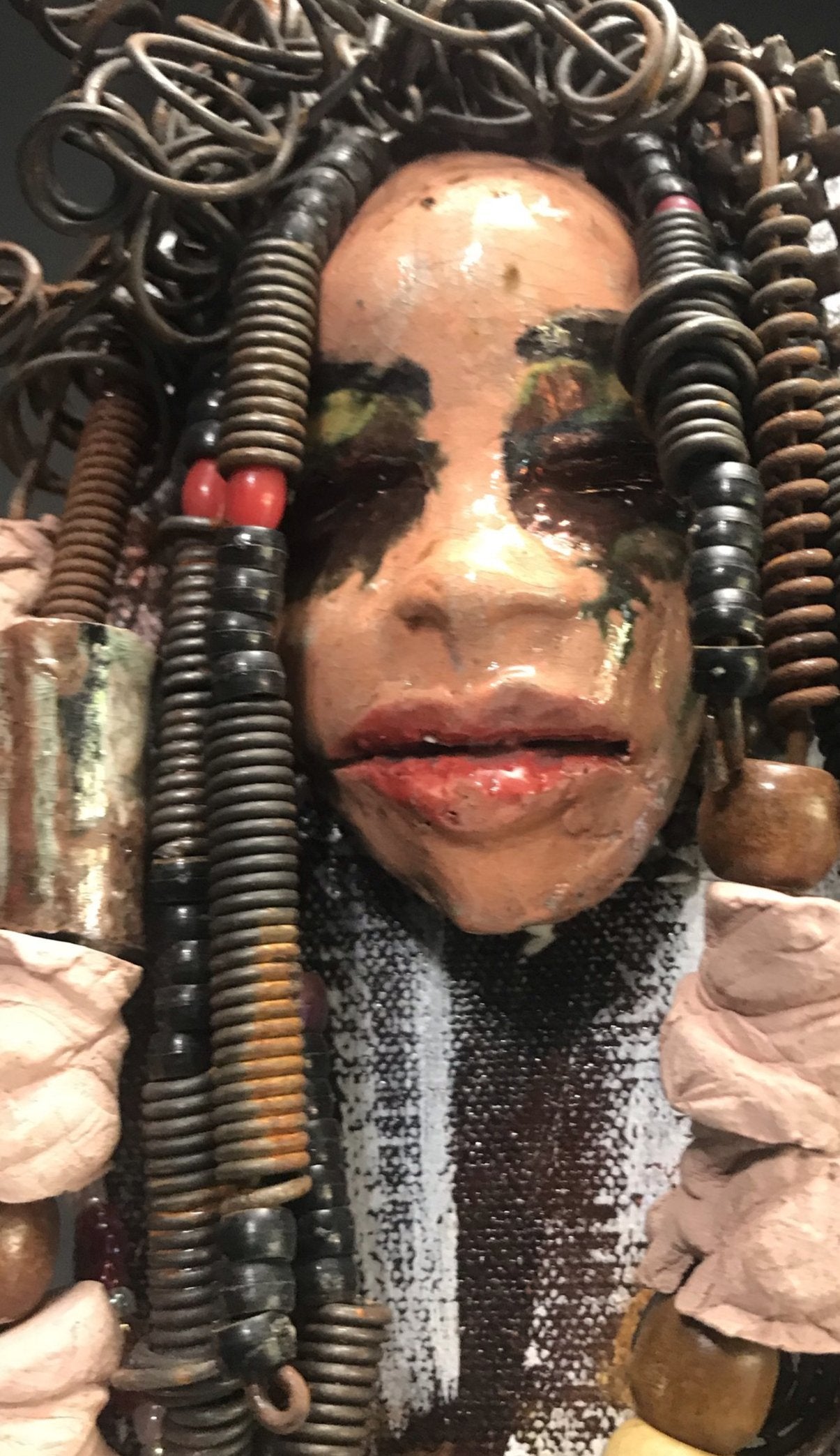 Kamara is uniquely mounted on a painted 6"x 4"x 2" canvas. It weighs 1.6lbs. Her face is formed with hand coiled wire, raku beads, textured brown cloth, and multi color raku beads. Kamara's face beams with pale pink crackle glaze and ruby red lips. Kamara is ready to be hung in a special place!