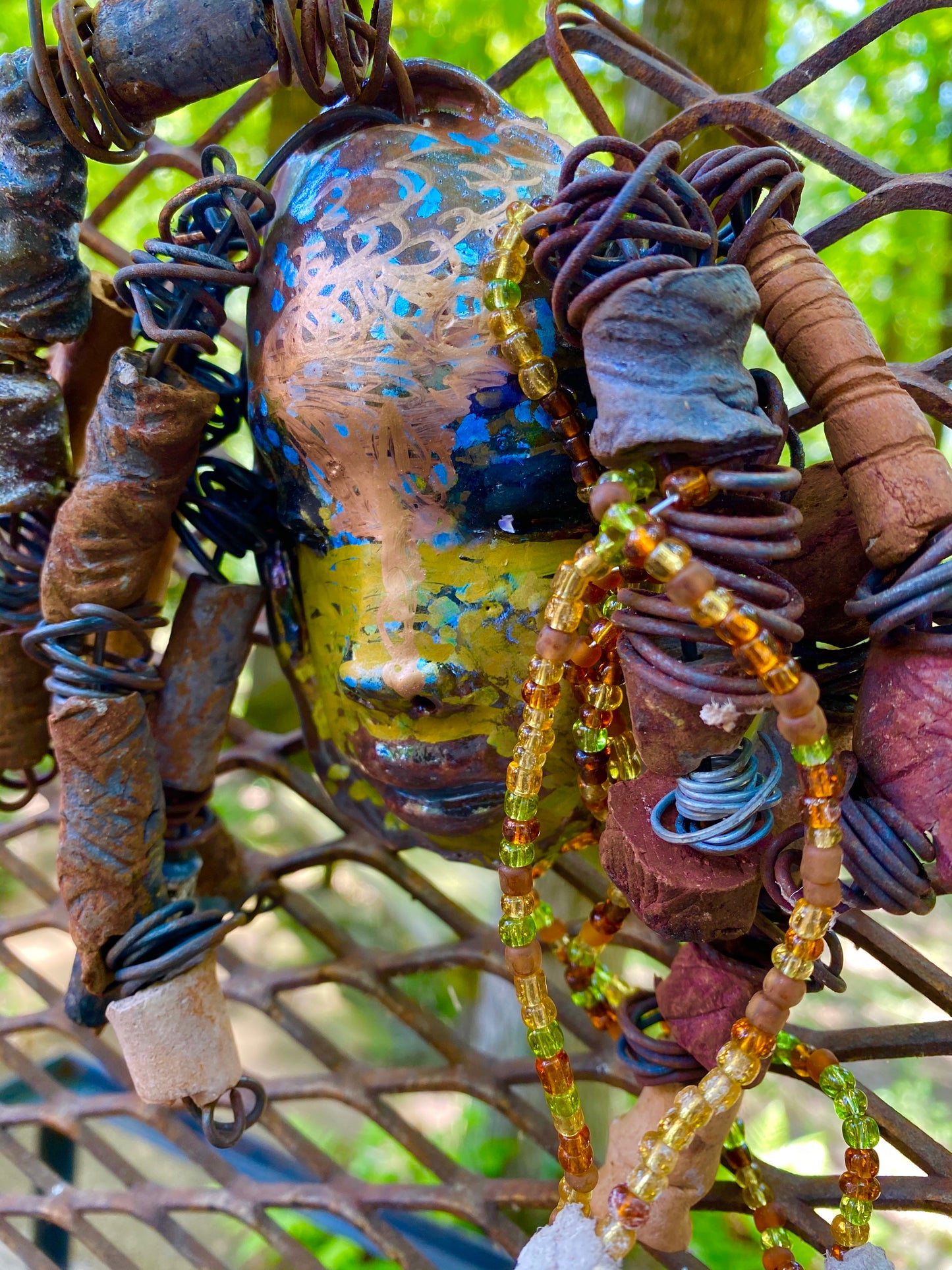 I started making mask soon after seeing authentic African artwork at the Smithsonian Museum of African Art. I was in total awe. Marali means she who listen was inspired by my visit there. Marali has a two tone metallic blue copper gold complexion. She is 7" x 5" and weighs 14 ozs. Marali has over 20 handmade raku fired beads. She has over 50 mini amber bead twisted as hair. Marali has over 6 feet of copper coiled 16 gauge wire hair.