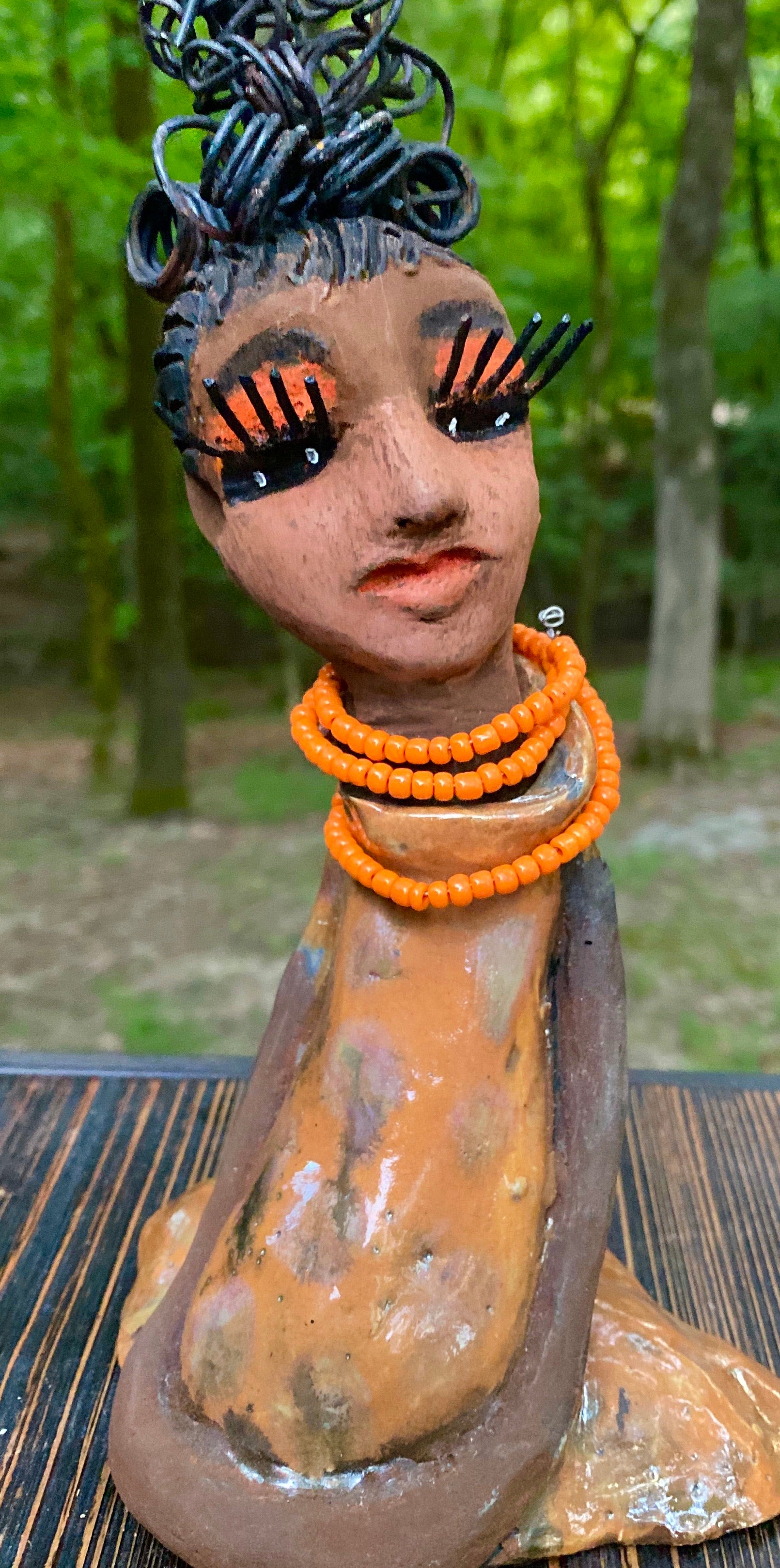 Meet Abimbola ! Abimbola stands 7' x 4"x 2" and weighs 1.3 lb. She has bright eyes and a nice honey brown complexion Abimbola  has over 5 feet of 16 gauge wire hair wrapped in a bun. Her long trademark arms rest at her side. Abimbola dress is a loving glossy orange mix with copper flashes. Abimbola is waiting for you to invite her into your home!