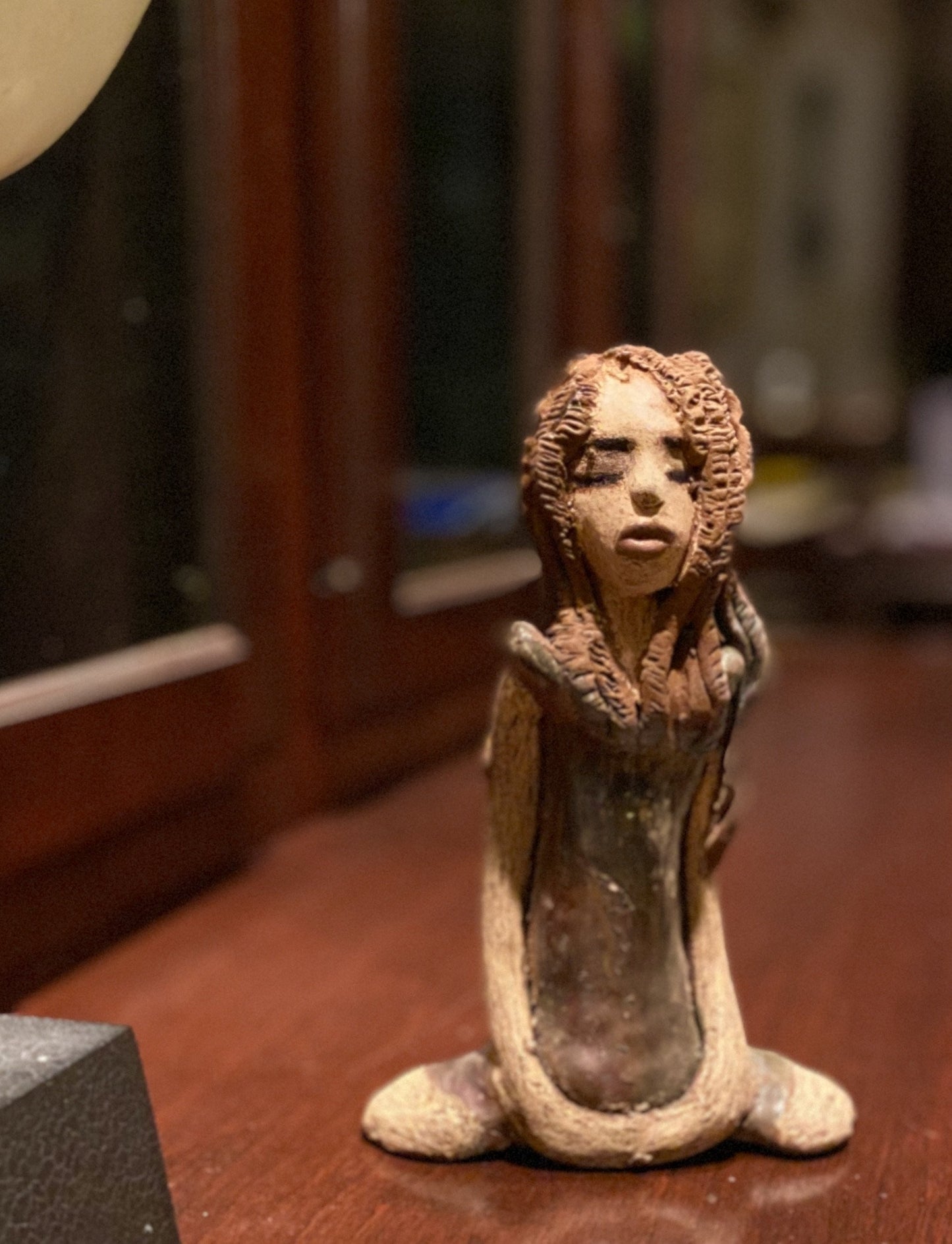 Amani stands 8" x 5" x 2.5" and weighs 1.03 lbs. She has a lovely beige brown complexion with long etched braided clay hair. Amani long loving arms rest beside her copper green dress. Amani is a sophisticated lady that will grace your home.