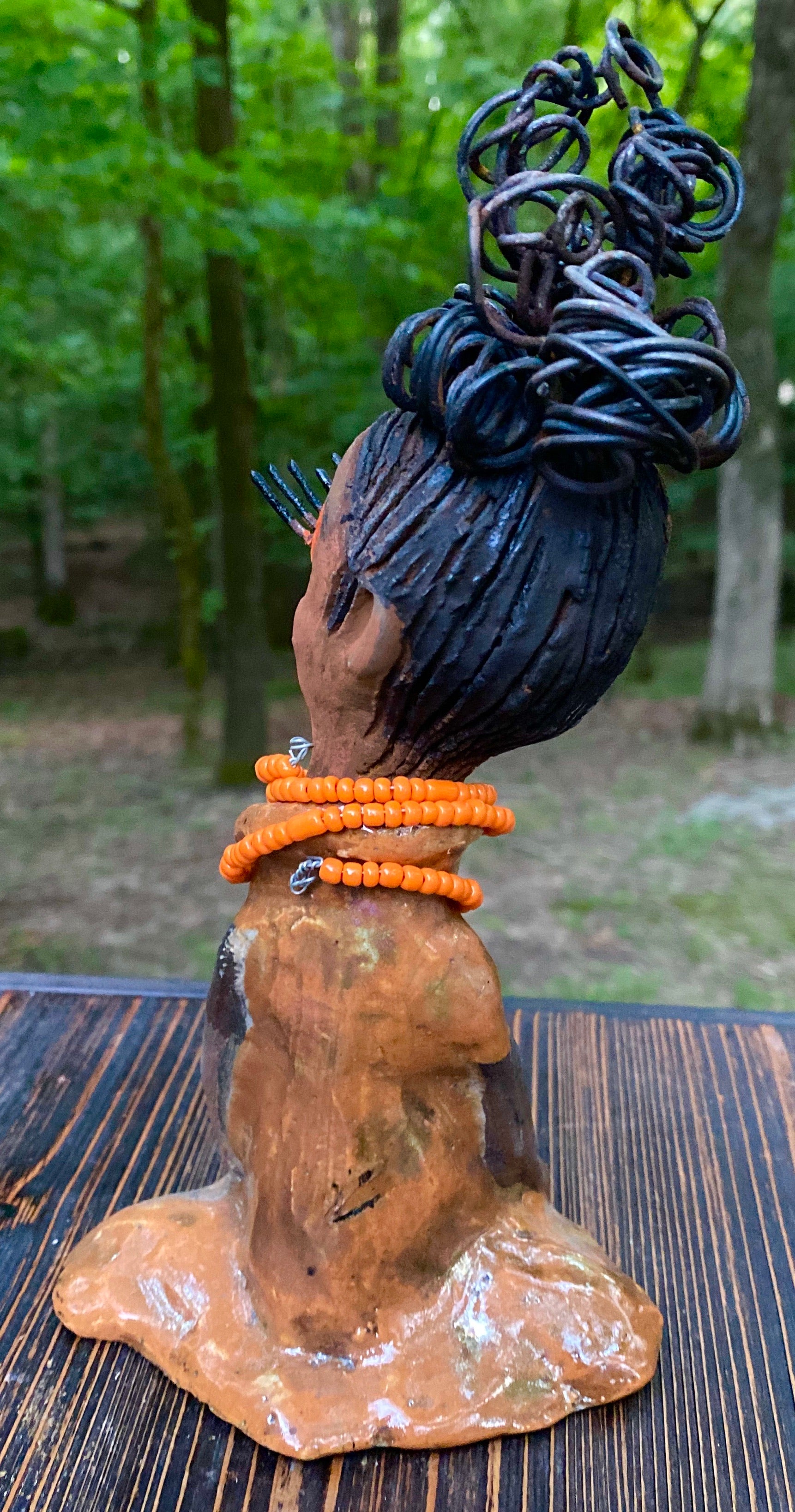 Meet Abimbola ! Abimbola stands 7' x 4"x 2" and weighs 1.3 lb. She has bright eyes and a nice honey brown complexion Abimbola  has over 5 feet of 16 gauge wire hair wrapped in a bun. Her long trademark arms rest at her side. Abimbola dress is a loving glossy orange mix with copper flashes. Abimbola is waiting for you to invite her into your home!