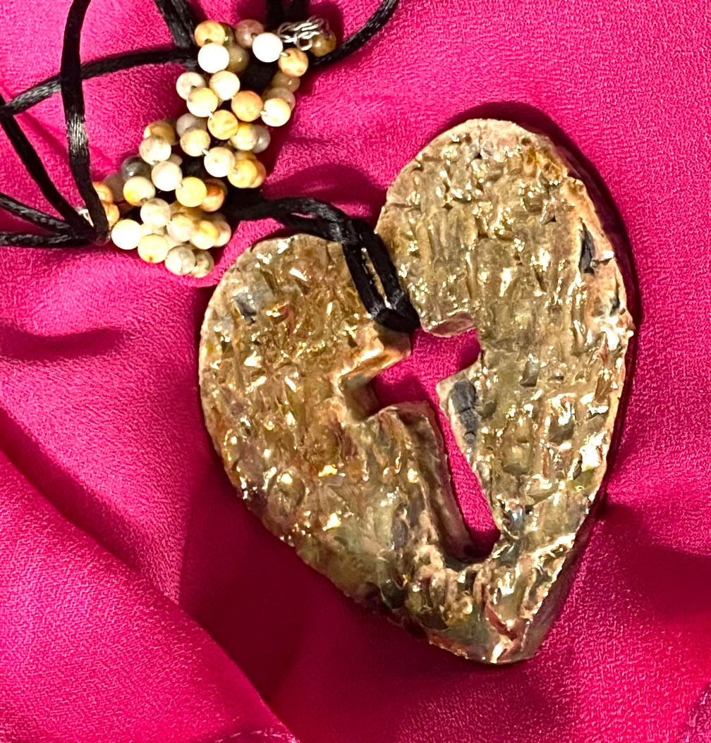 Have A Heart ! Each heart pendant is handmade with love! It is 3"x 3" and weighs approx. 3ozs. This pendant has a white and gold metallic raku glazes that renders a unique translucent  patina. The heart has a textured with cut out cross pattern . It holds a spiral of multicolored mini beads on a spiral copper wire. This pendant has a nice 12" black suede cord!