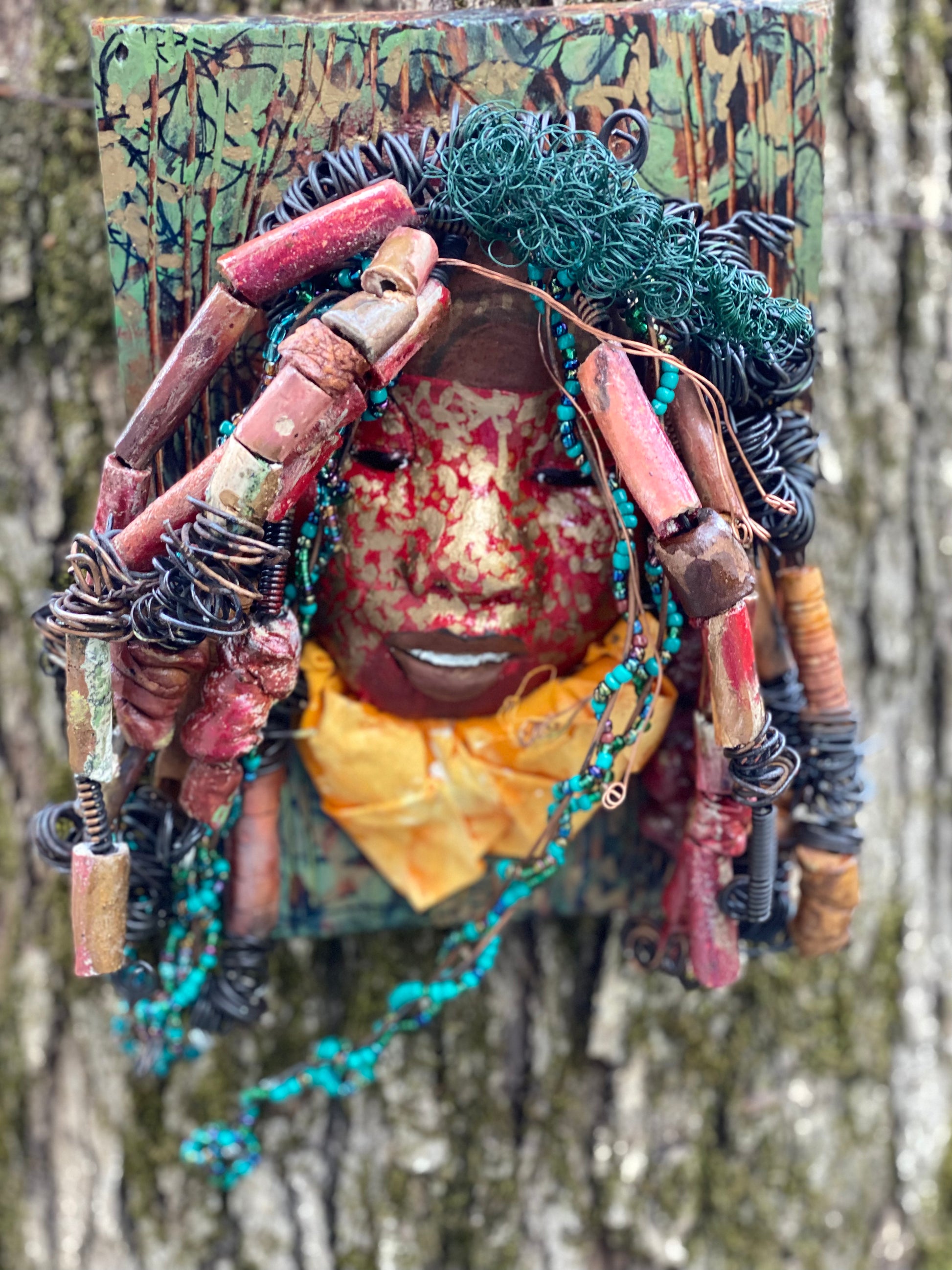 Deandra is one of a new 2022  series of tribal masks that are mounted on wood. I started making art soon after seeing authentic African artwork at the Smithsonian Museum of African Art. I was in total awe. Deandra is 7” x 10 x 1 and weighs 3.7 lbs.  She has a contagious smile. 25 handmade raku fired beads Over 60 mini 6mm multi colored beads  Over 60 feet of 16 and 24 gauge twisted wire for hair!