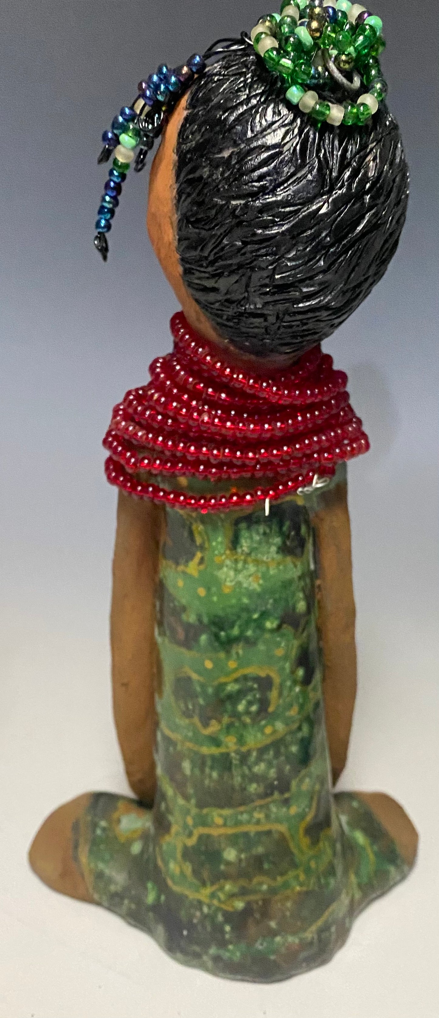 Meet Julia! Julia stands 10" x 6" x 5" and weighs 1.10 lbs. She has a lovely two tone honey brown complexion. Julia black etched hair has two beaded braids! Julia has a metallic antique copper green glazed dress. With her eyes opened and her long arms at her side, she has something to say! " I am just waiting on you to invite me into your home!" Julia will place a smile on your face and spark interesting conversation!