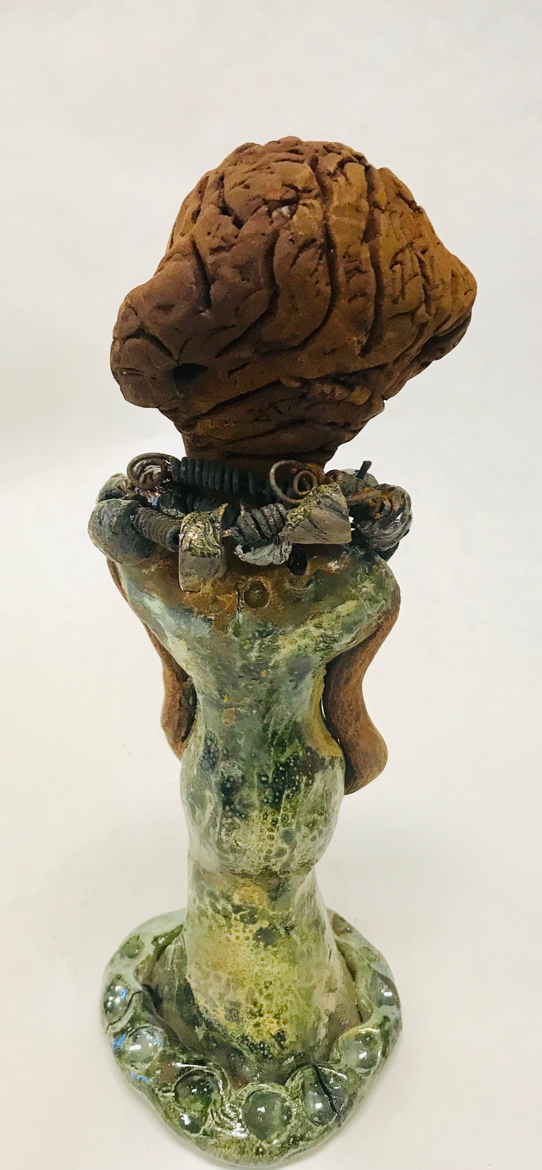 Greta stands 11" x 4" x 4" and weighs 2.5 lbs. She has a lovely honey brown complexion with  reddish brown lips. She has a braided hairstyle.  Greta has a colorful metallic green antique copper glazed dress. She wears two raku beaded necklaces. With long eyes slightly opened, Greta has hopes of finding a new home.    Greta will attract and spark conversation with guest in your home!