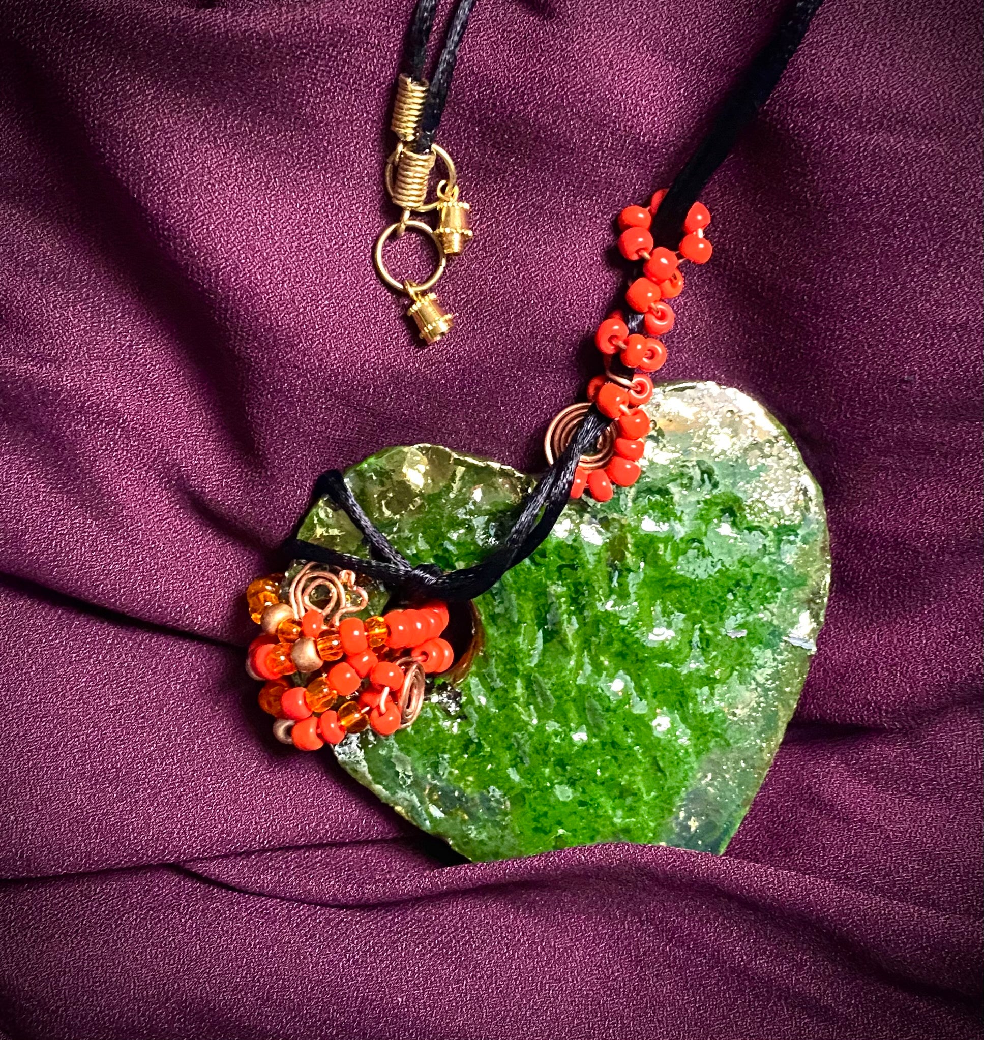 Have A Heart ! Each heart pendant is handmade with love! It is 3"x 3" and weighs approx. 3ozs. This pendant has a green metallic raku glazes that renders a unique translucent  patina. The heart has a textured pattern . It holds a spiral of green mini beads on a spiral copper wire. This pendant has a nice 12" black suede cord!