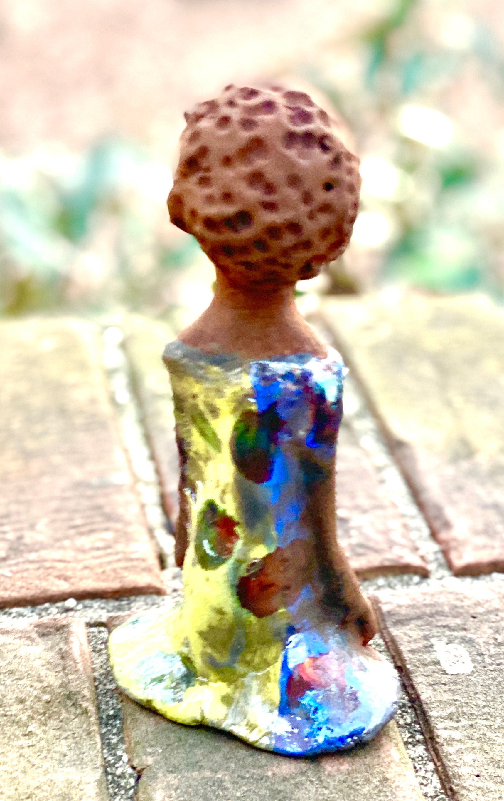 Adisa stands 7' x 4"x 2" and weighs 10.3 ozs. She has bright  dark eyes and a nice honey two tone brown complexion Her long trademark arms rest at her side. Adisa dress is a loving glossy blue and yellow mix with copper flashes.