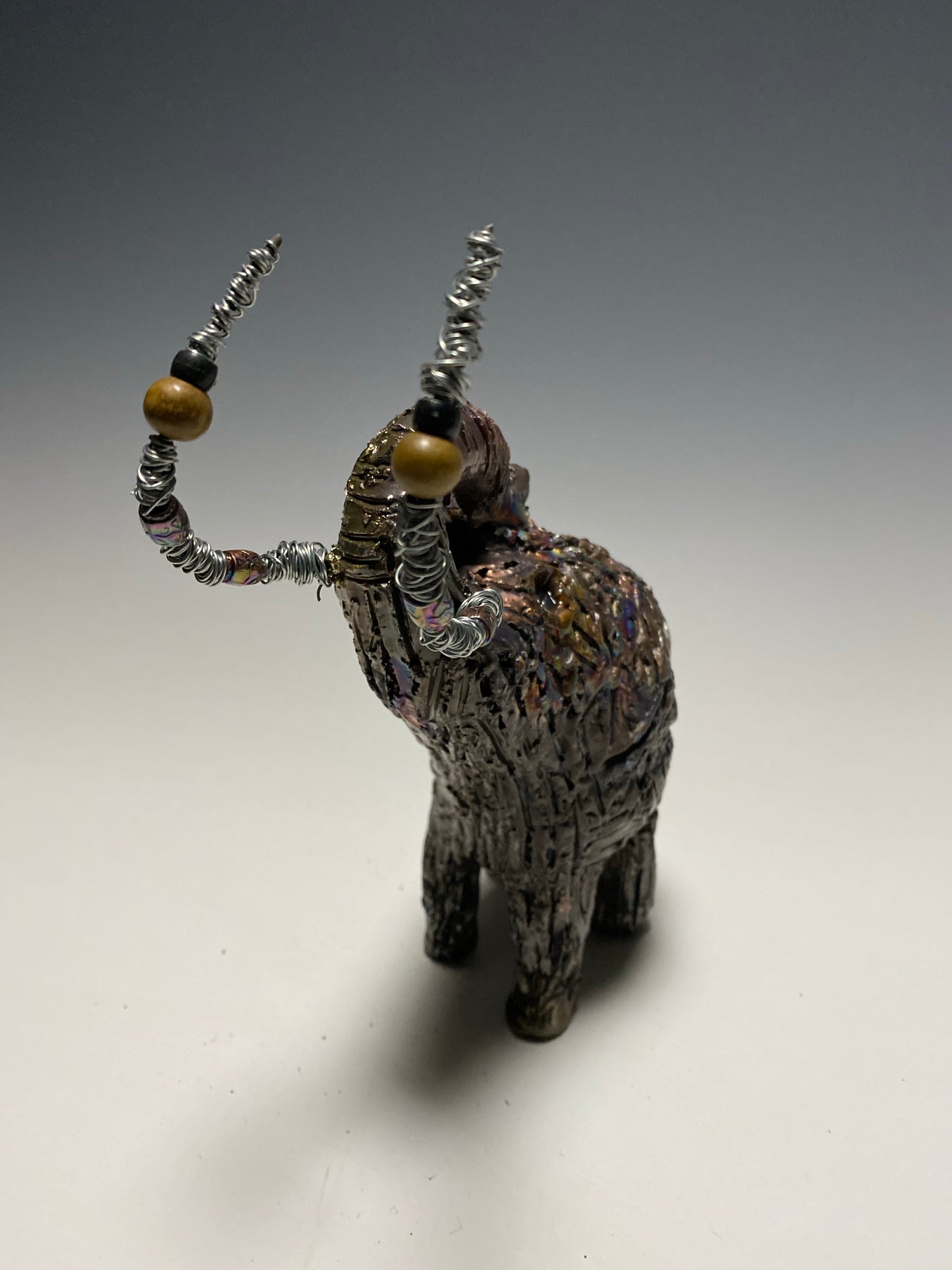 Raku Elephant Have you HERD!!!!!! Just one of these lovely Raku Fired Elephant will make an excellent gift for your friend, sorority or for your home’ special place centerpiece. 6" x 4" x 4" 1lbs Wood beaded with silver tusk Beautiful metallic raku colors For decorative purposely only.