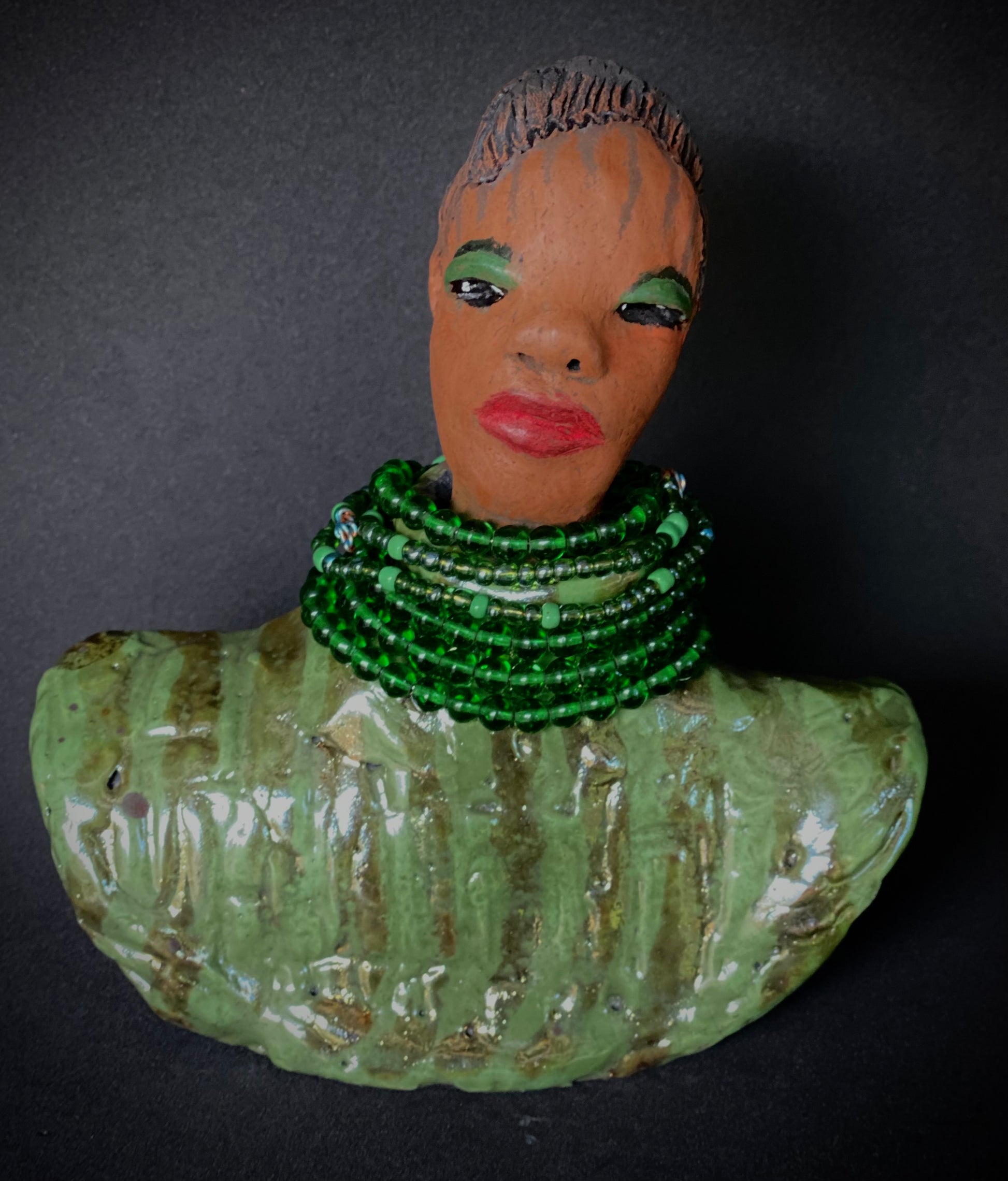 Delia looks up with joy and anticipation! Delia stands 7"x 6" x 3" and weighs 1.50 lbs. She wears an awesome metallic green textured copper robe. Delia has braided clay hair up in a bun. She has a honey brown complexion. Delia could make an excellent gift for your BFF! Delia will make for great conversation in your home. Free Shipping! Check out our Shipping  and Return policy