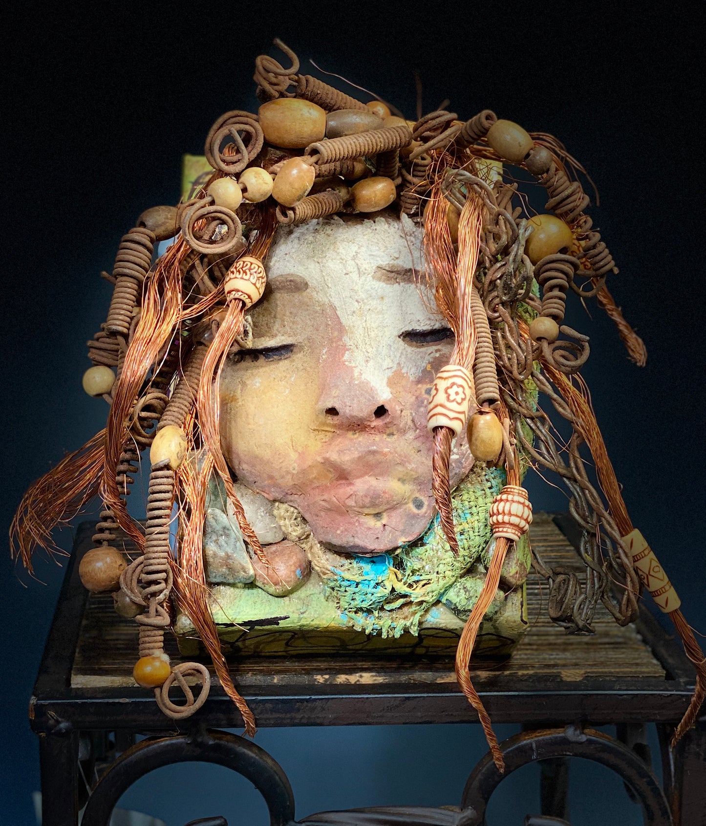 I started making art soon after seeing authentic African artwork at the Smithsonian Museum of African Art. I was in total awe. Lulu was inspired by my visit there. Lulu is uniquely mounted on a painted 6"x 4"x 2" canvas. It weighs 1.15 lbs. Her face has a two tone off white and earthy crackle glaze. Lulu has hand coiled wire, white and multi color beads, textured earthy cloth..