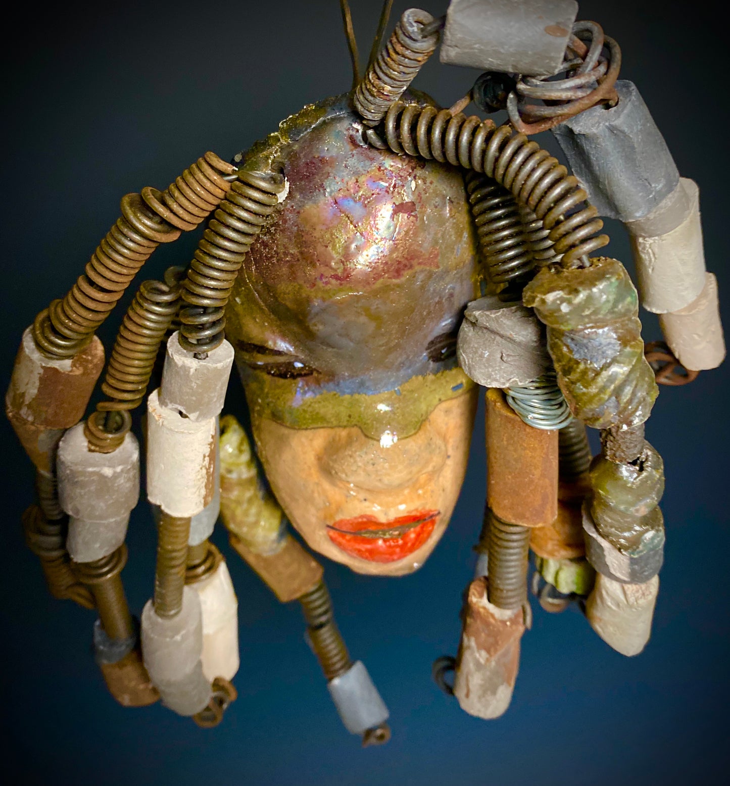 I started making art soon after seeing authentic African artwork at the Smithsonian Museum of African Art. I was in total awe. Kenna was inspired by my visit there. Kenna has a two tone light and dark honey metallic complexion. Her hair can be adjusted up to 11" x 10" and weighs 1. lbs Kenna has over 20 handmade multicolored raku fired beads. She has over 20 feet of coiled 16 gauge wire hair. Kenna is ready for display!