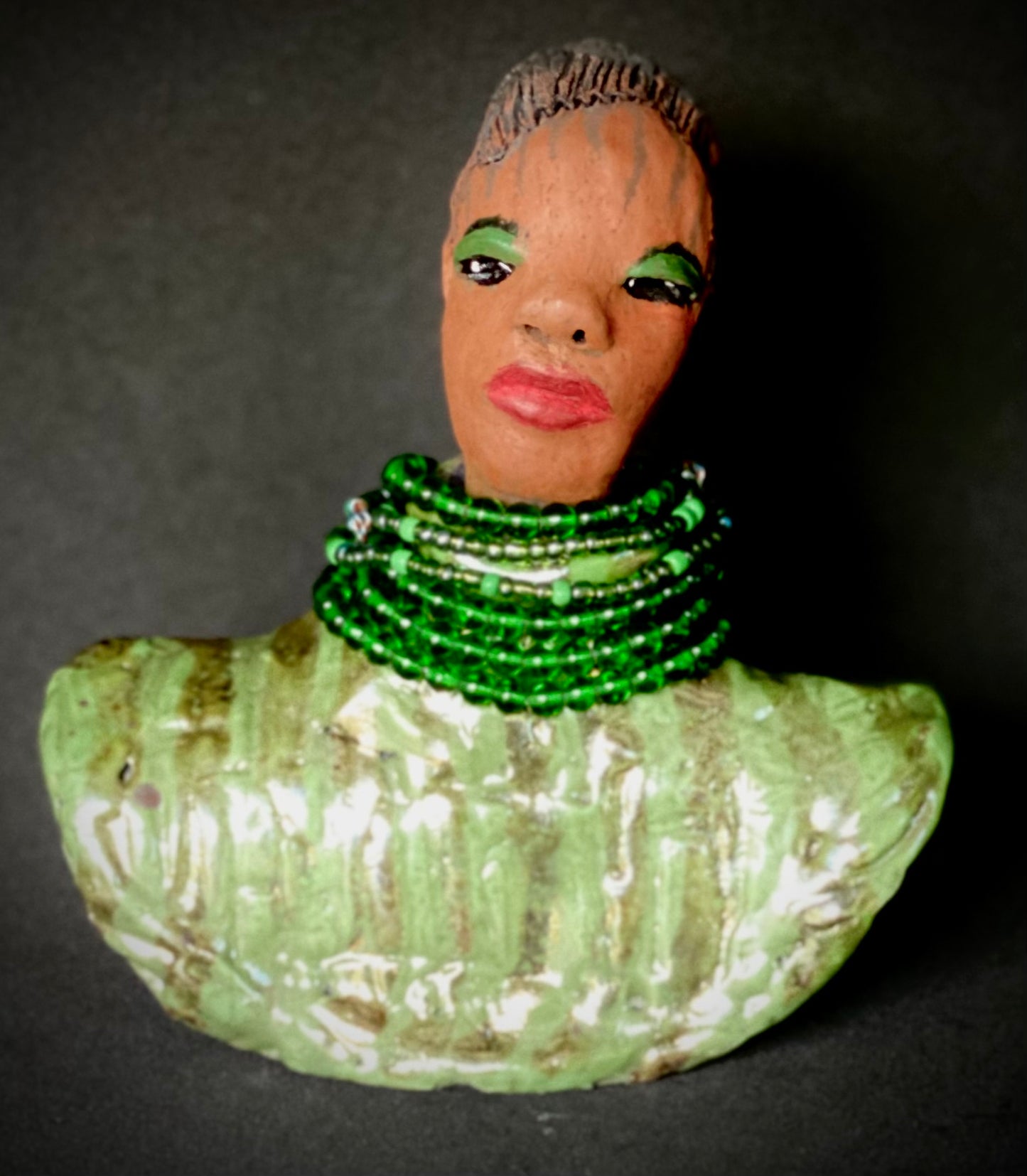 Delia looks up with joy and anticipation! Delia stands 7"x 6" x 3" and weighs 1.50 lbs. She wears an awesome metallic green textured copper robe. Delia has braided clay hair up in a bun. She has a honey brown complexion. Delia could make an excellent gift for your BFF! Delia will make for great conversation in your home. Free Shipping! Check out our Shipping and Return policy