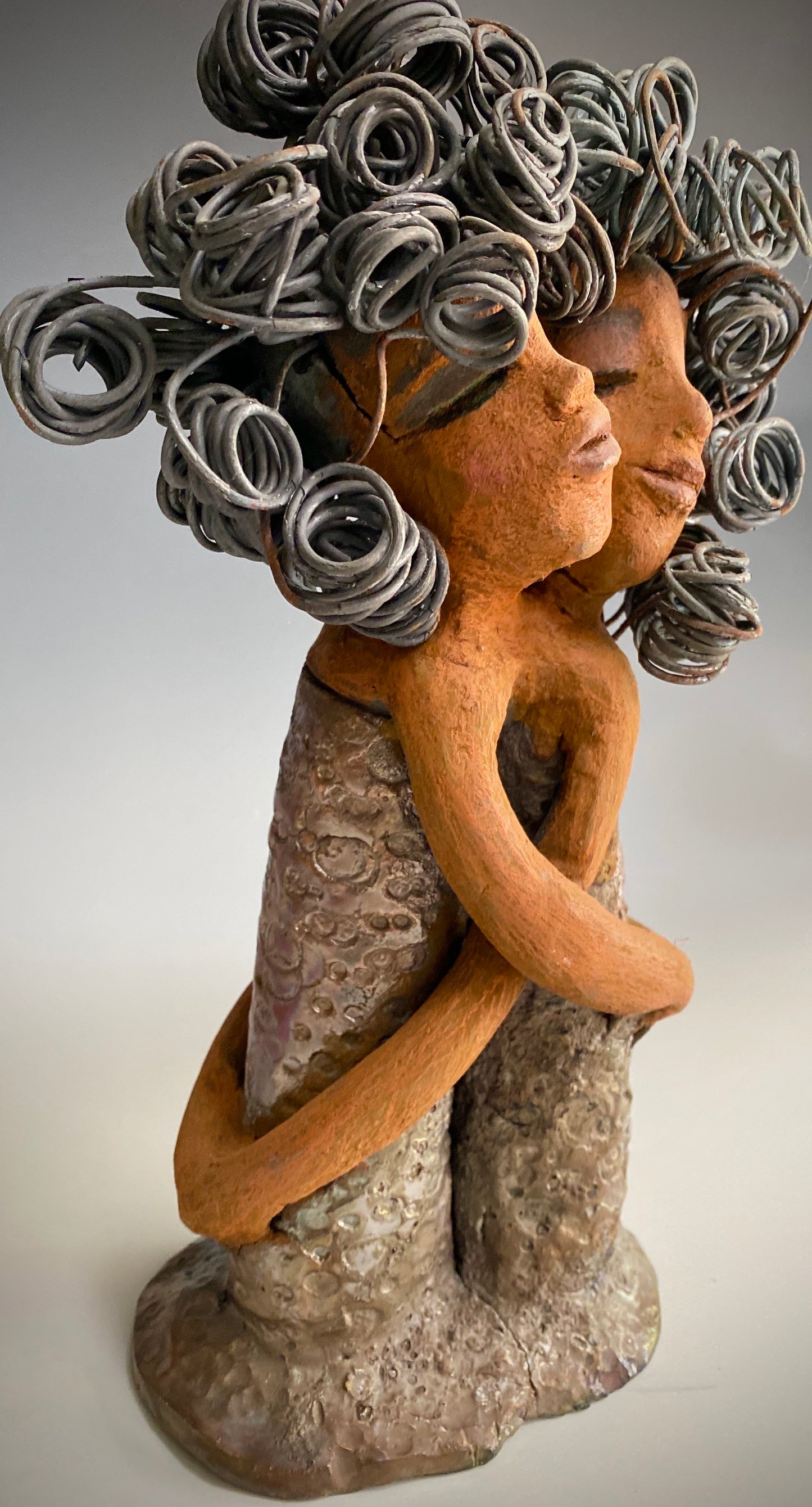 Sister Love is a raku fired sculpture. Raku is a specialized firing technique that involves high heat and open flames. Sister Love stands 11" x 5" x 3" and weighs 2.06 lbs. Combined they have over 45 feet of curled 16 gauge wire hair. The dresses are textured with an antique copper glaze. They have lovely honey brown complexions and long loving arms. Sister Love is inseparable! Give them a special place in your home. Free Shipping!