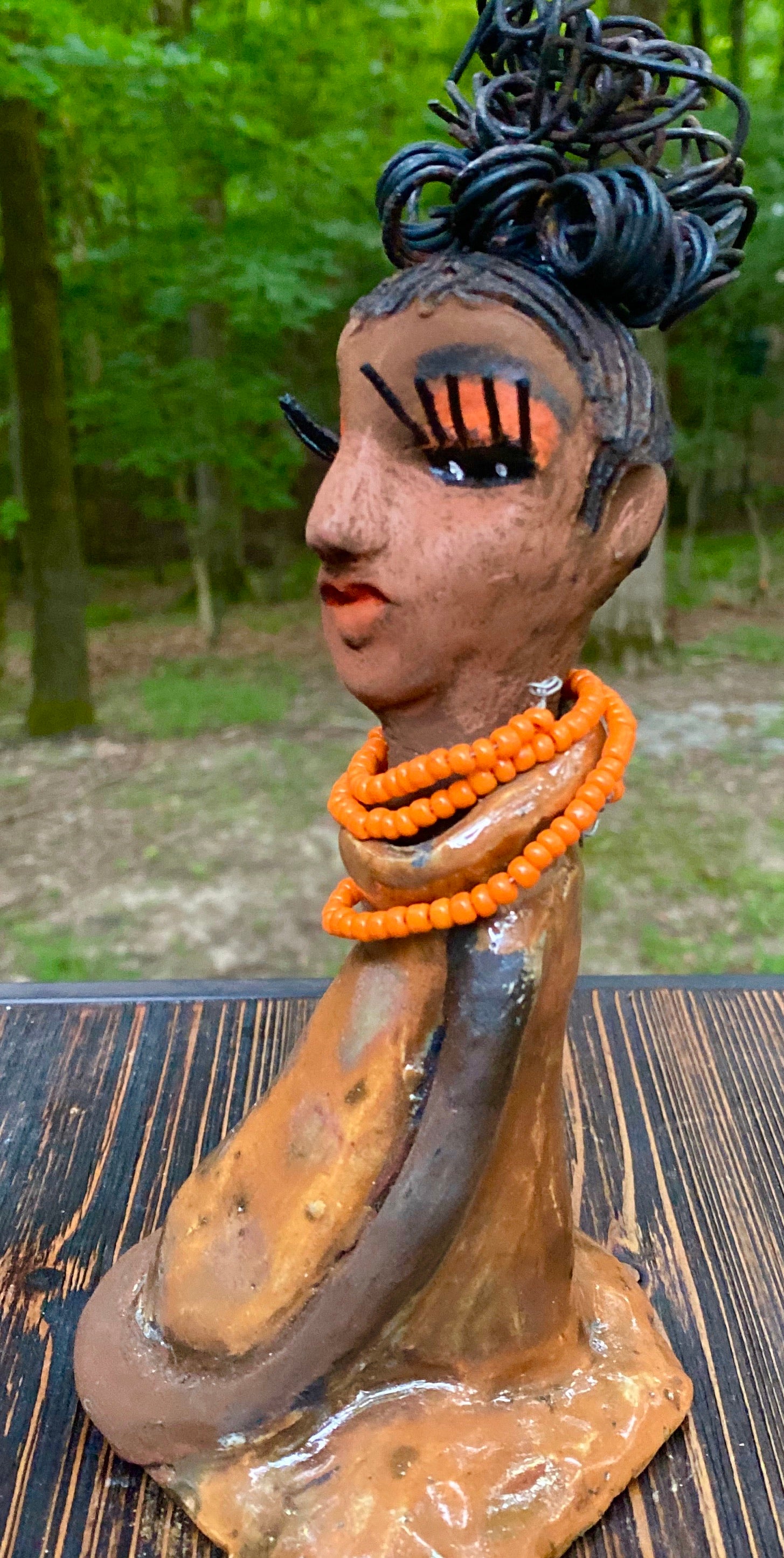 Meet Abimbola ! Abimbola stands 7' x 4"x 2" and weighs 1.3 lb. She has bright eyes and a nice honey brown complexion Abimbola  has over 5 feet of 16 gauge wire hair wrapped in a bun. Her long trademark arms rest at her side. Abimbola dress is a loving glossy orange mix with copper flashes. Abimbola is waiting for you to invite her into your home!