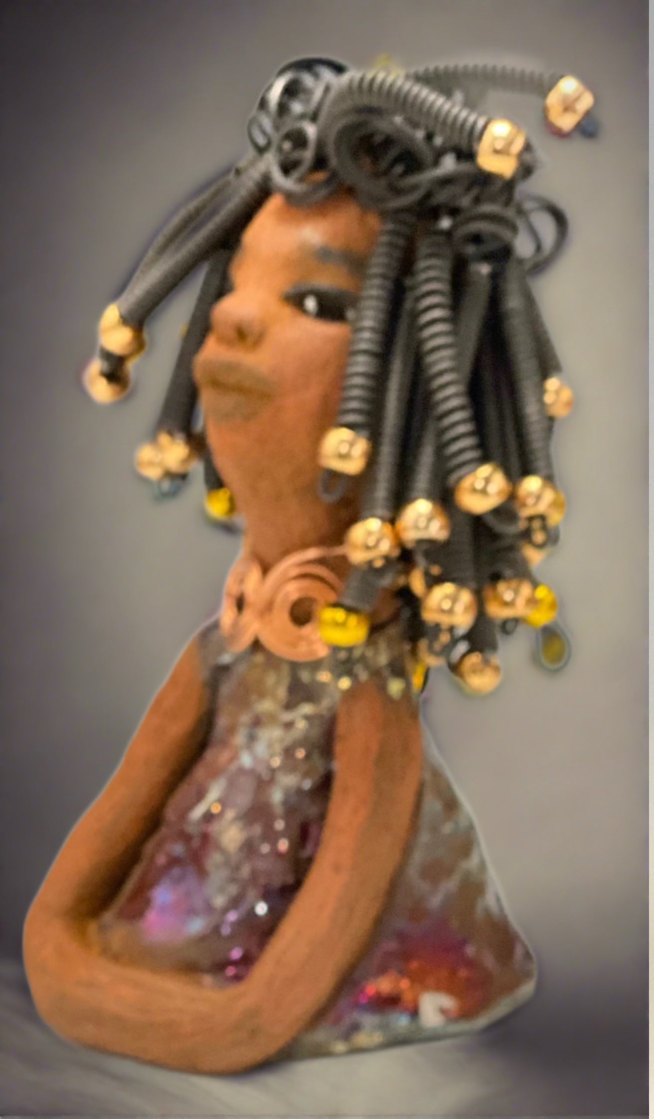 Meet Alexus Alexus stands 7.5" x 4" x 4" and weighs 1.05 lbs. She wears a lovely glossy metallic gold dress adorn by a spiral copper necklace. Alexus has over15 feet of coiled wire hair with gold beads.. Alexus appears to sit in a yoga pose. Her long arms rest at her side. Alexus is a great starter piece from the Herdew Collection!