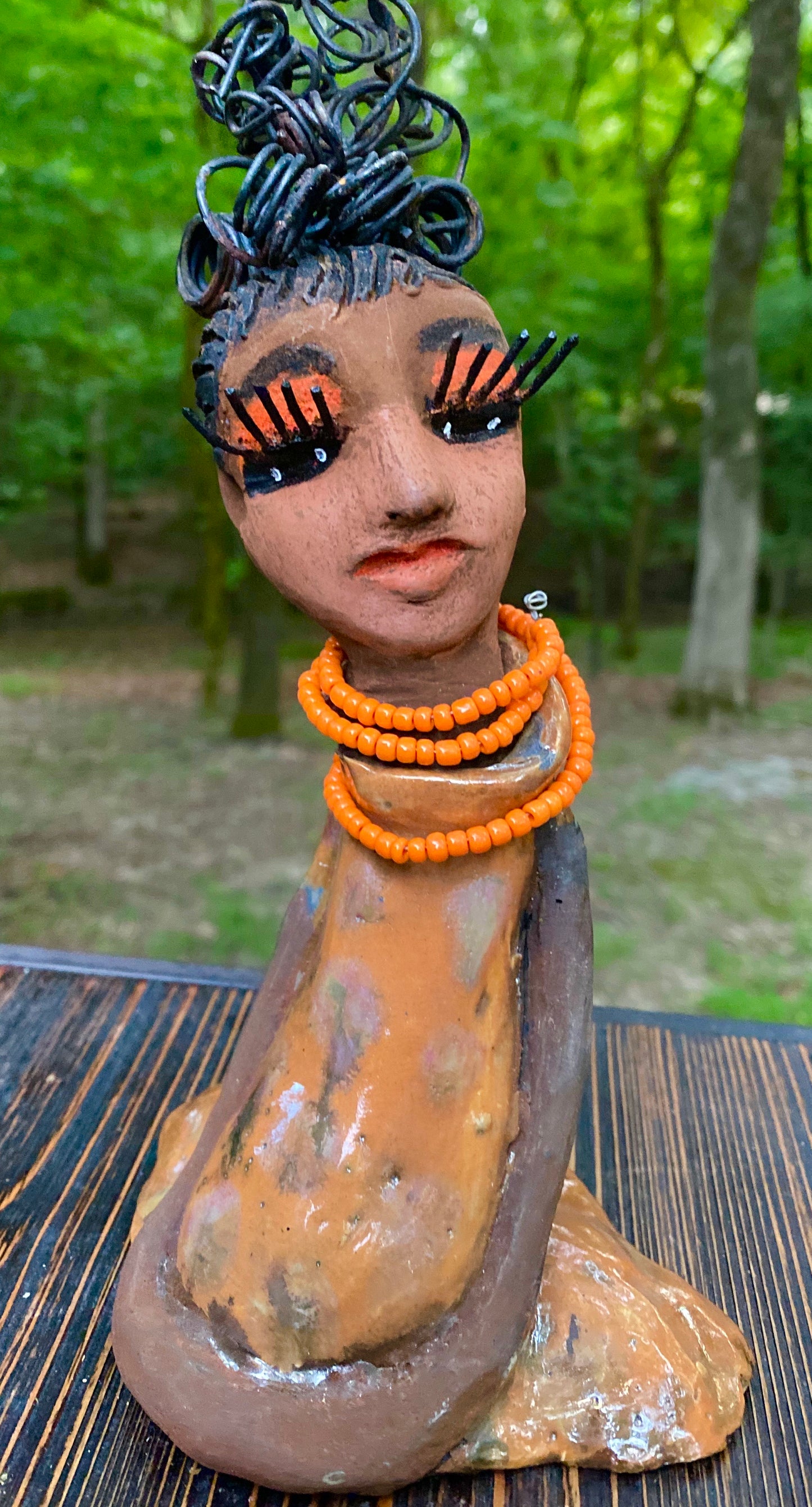 Meet Abimbola ! Abimbola stands 7' x 4"x 2" and weighs 1.3 lb. She has bright eyes and a nice honey brown complexion Abimbola  has over 5 feet of 16 gauge wire hair wrapped in a bun. Her long trademark arms rest at her side. Abimbola dress is a loving glossy orange mix with copper flashes. Abimbola is waiting for you to invite her into your home!
