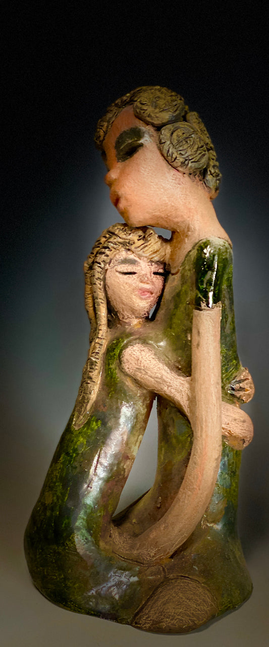 "Hold Me Mama has a very similar look and feel as                             Girl Talk with my Mom". Hold Me Mama depicts the bond between a mother and child". They stand 10" x 5" x 5" and weighs 2.8 lbs. Mother and Child has honey brown complexions  with etched copper colored  clay hair. They wear green/ copper raku fired glossy dresses.  Mother assures her daughter  that everything will be alright!