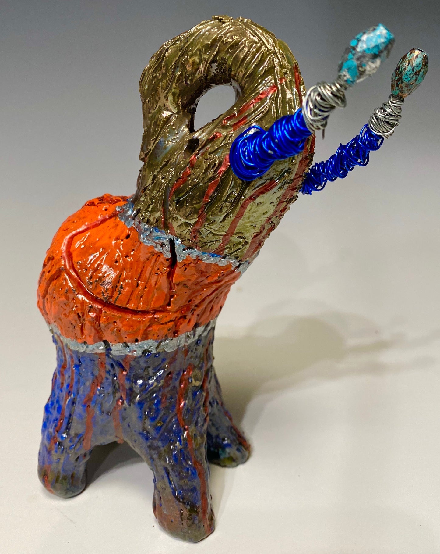 Have you HERD!!!!!! Just one of these lovely Raku Fired Elephant will make an excellent gift for your friend, sorority or for your home’ special place centerpiece. 7" x 4" x 4" 15 ozs. Blue wire beaded blue and silver tusk Beautiful metallic blue and orange raku colors For decorative purposely only.