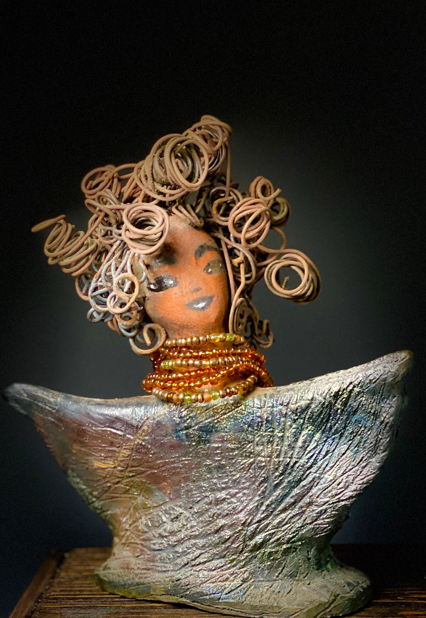 Lizzie Got Big Hair! Lizzie stands 8" x 7" x 2.5" and weighs 1 lb. Her robe is textured with a multicolored metallic copper glaze. Lizzie has really Big Hair. The hair is over 25 feet of curly 16 gauge wire. Her complexion is a lovely cocoa brown. Lizzie has an angelic pose with her arms up in adoration. Give Lizzie a specail place in your home!