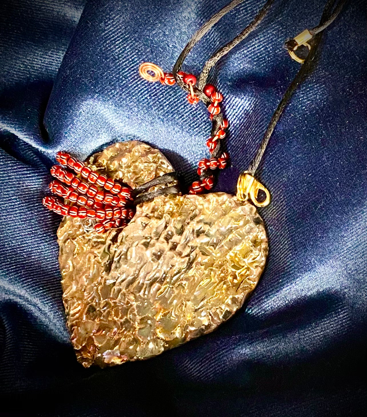 Have A Heart ! Each heart pendant is handmade with love! It is 3"x 3" and weighs approx. 3ozs. This pendant has a white and gold metallic raku glazes that renders a unique translucent patina. The heart has a textured with cut out cross pattern . It holds a spiral of multicolored mini beads on a spiral copper wire. This pendant has a nice 12" black suede cord!