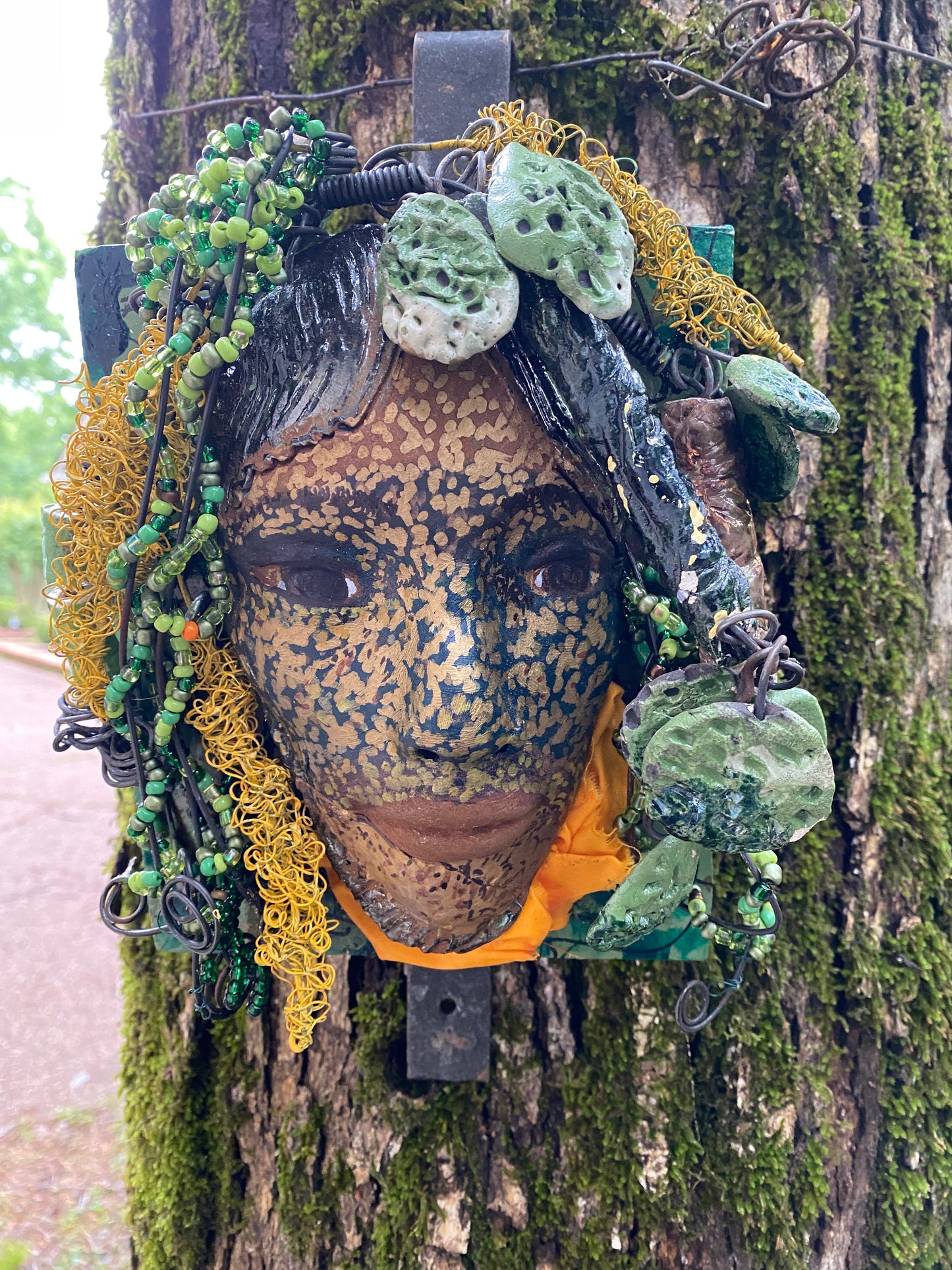 Casey is one of a new 2022 series of tribal masks that are mounted on wood. I started making art soon after seeing authentic African artwork at the Smithsonian Museum of African Art. I was in total awe. Casey is 6” x 7 x 1 and weighs 1.13 lbs. She has a contagious smile. Casey's face is speckled gold. 12 handmade raku fired beads Over 60 mini 6mm multi colored beads Over 60 feet of 16 and 24 gauge twisted wire for hair! Over two weeks to complete! Casey is ready to be mounted inside or outdoors!