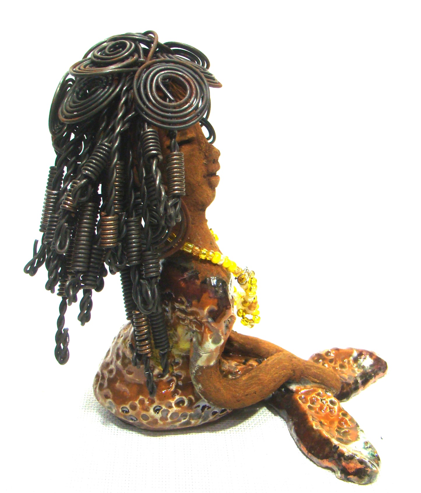 Meet Isabella the Mermaid! Isabella stands 7' x 4" x 6" and weighs 1.08 lbs.. Isabella has a lovely brown complexion. Her long loving arms are crossed in her lap. Isabella has over 20 feet of wire hair. It took over two hours to fix her hair! Isabella has a metallic yellow swimsuit with flashes of copper. She wears a yellow beaded necklace. Isabella appears to have something on her mind!