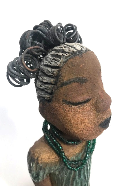 Meet Katie!      Katie stands 12" x 6.5" x 5.5"and weighs 2.13 lbs.     Katie has a lovely two tone honey brown complexion.     She has a nice wire pony tail behind her smokey black hair.     Katie has a gold band around her long loving arms.     Her dress is an alligator green with streaks of copper.     Katie wears an emerald beaded necklace.  Katie sits patiently and  waits on a new home. Free Shipping!