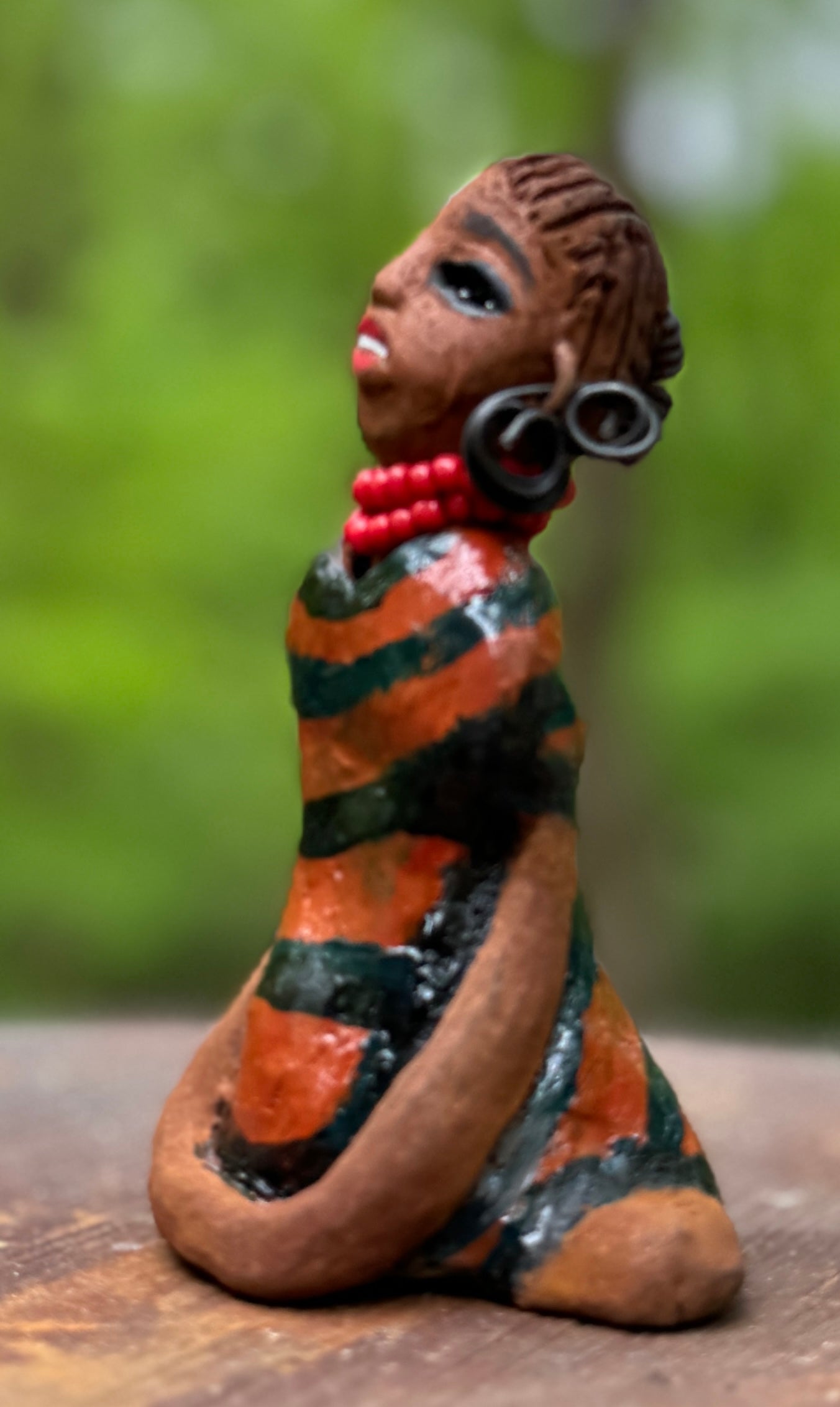 Experience the bold and fearless Shiba from the Herdew Collection! This raku fired sculpture stands tall at 5" x 3" x 3" and weighs a brave 7 ozs. Clothed in a striking orange and black dress, Shiba's coiled wire hair stretches over 1 foot. With confident outstretched arms, she strikes a yoga pose. Begin your collection with the captivating Kitty and embrace adventure!