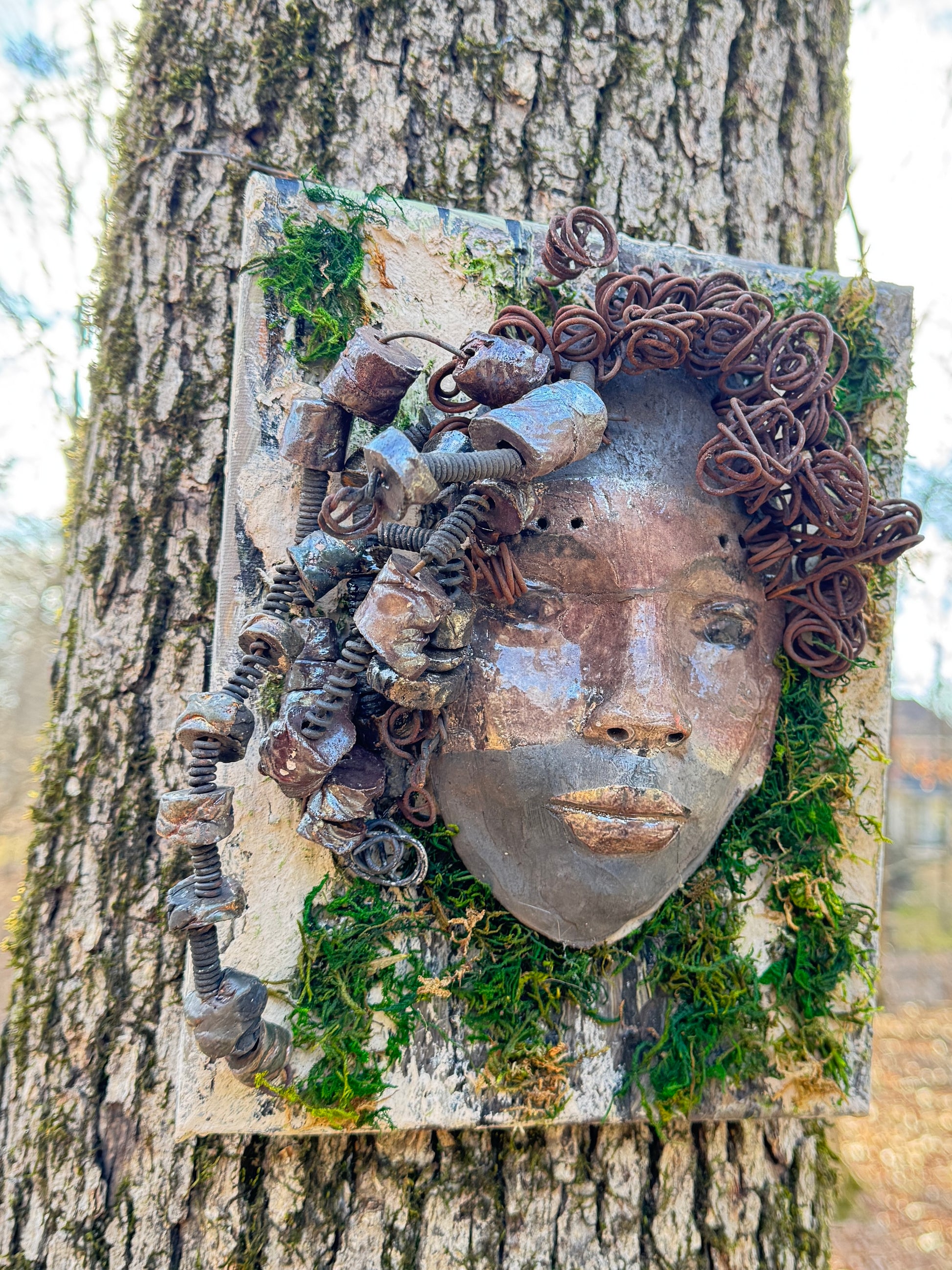 Kai is an 8 x 10 canvas mounted mixed media mask. It weighs approximately 3 pounds and features over 20 feet of 16 gauge wire and 20 handmade Raku fired beads. Her two tone complexion is highlighted by the lush tree bark emulated on the canvas.