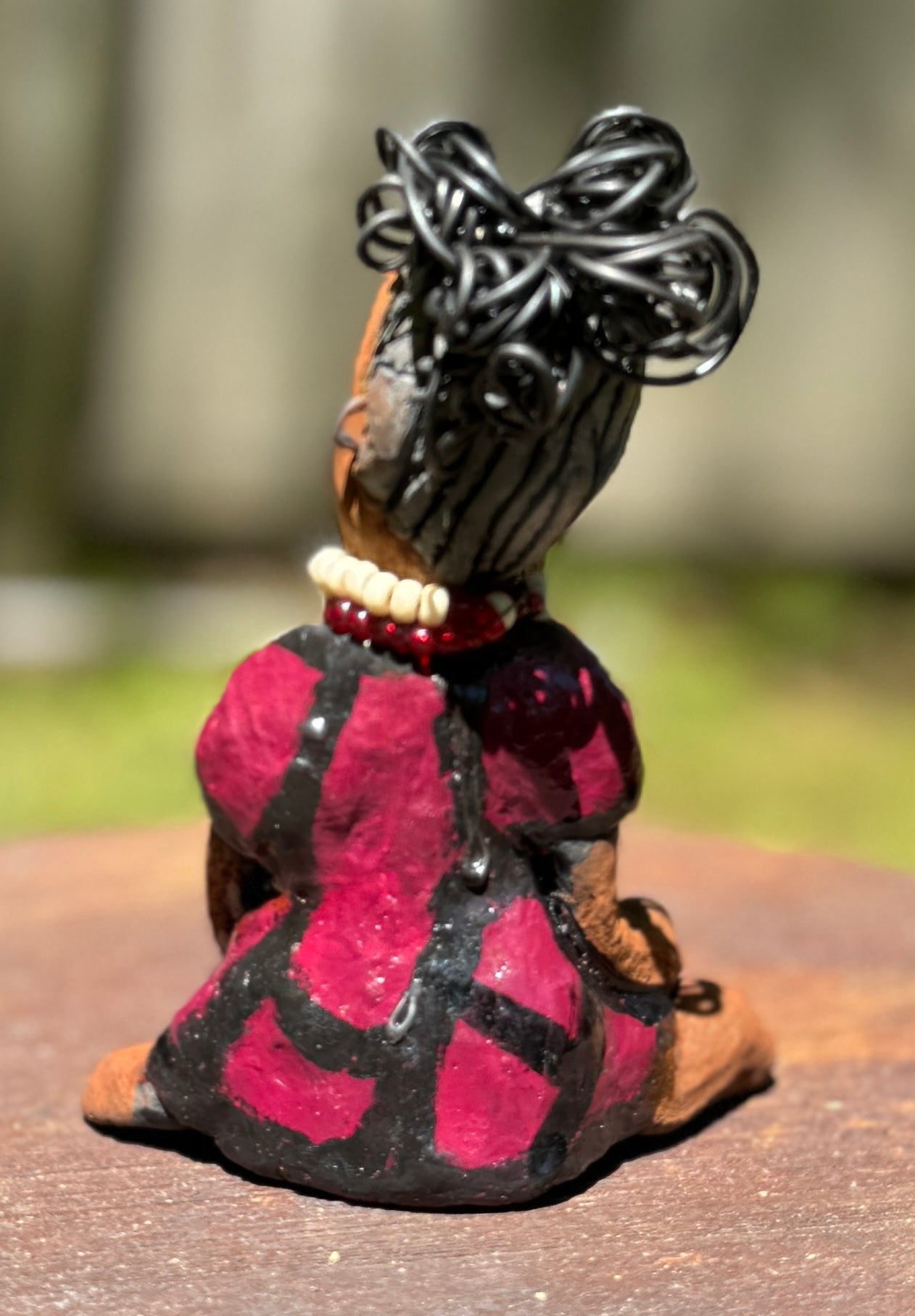 Embark on a thrilling journey with Tia from the Herdew Collection! This daring raku fired sculpture stands tall at 6" x 4" x 3" and weighs a fearless 9.6 ozs. Adorned in a striking geometric print dress, Tia's coiled wire hair stretches over 1 foot. With determined outstretched arms, she strikes a powerful yoga pose. Start your collection with the captivating Tia and embrace the thrill of adventure!