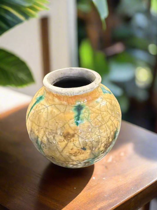 Discover the intricate details of this 4-inch tall and 3 1/2-inch wide and deep Yellow Crackle pottery piece, with an opening of 2 inches. Its striking spotted green accents enhance the overall aesthetic. Expertly crafted and fired using the raku technique, it is a must-have for any collector or admirer of pottery.