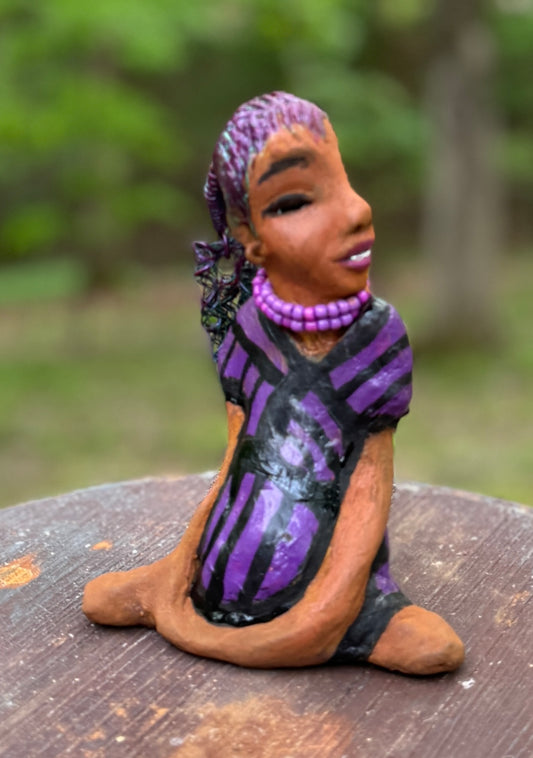 Zola is 7" x 5" x 3" raku fired scupture and weighs 12 ozs.<br>She wears a lustrous striped purple dress.<br>Her coiled wire hair is her crown of glory.<br><br>Zola sits in a yoga pose. Her expression is &nbsp;of curiosity. She will make an ideal beginning piece from the Herdew Collection!<br>Free Shipping