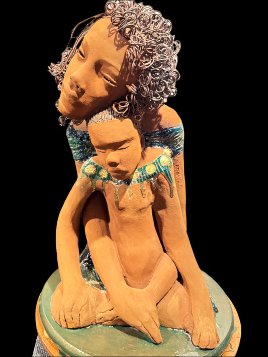 “A mother ‘s love is the first place we ever feel safe, silent, study, and strong”

This heartfelt ceramic sculpture by Lester Jones captures the quiet strength of a mother child bond. With her head gently resting against the child’s, the mother exudes calm and protection while the child leans into her embrace with trust and ease. This piece is approximately 20 inches height and 18 inches in width and depth.

Rendered in a warm earthy tone with coiled wire detailing the hair, the peace, radiates tenderness,
