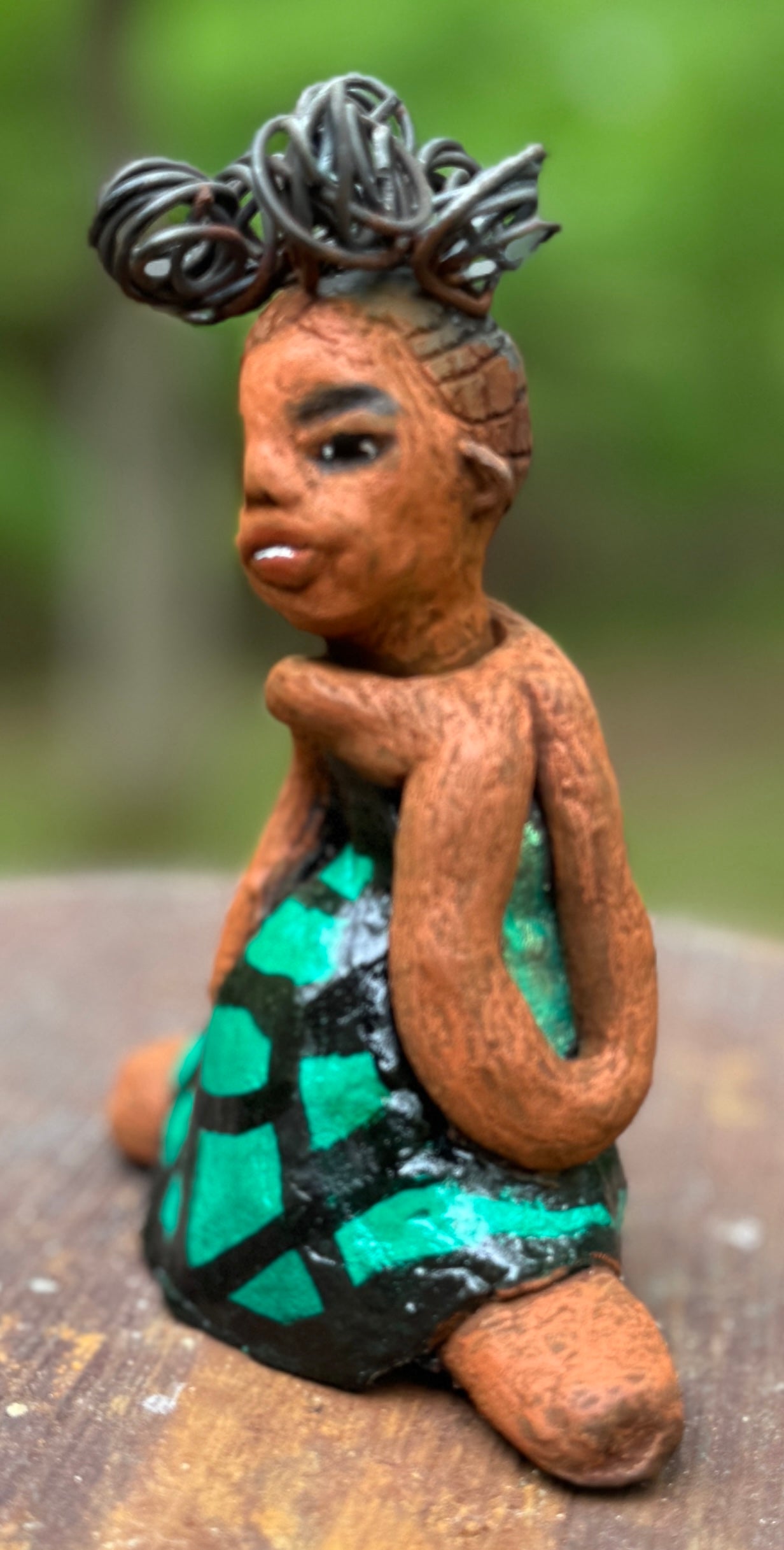 Discover Fayola, the bold figurine standing at 6" x 4” x 3” and weighing only 8.6 ozs, adorned in a striking black and green African print dress. With her hair styled in coils and her hands calmly resting in a yoga pose, Fayola emanates confidence. Join the Herdew Collection and embark on an exciting journey with our complimentary shipping and customer-friendly return policy. Don't hesitate to claim this unique treasure!