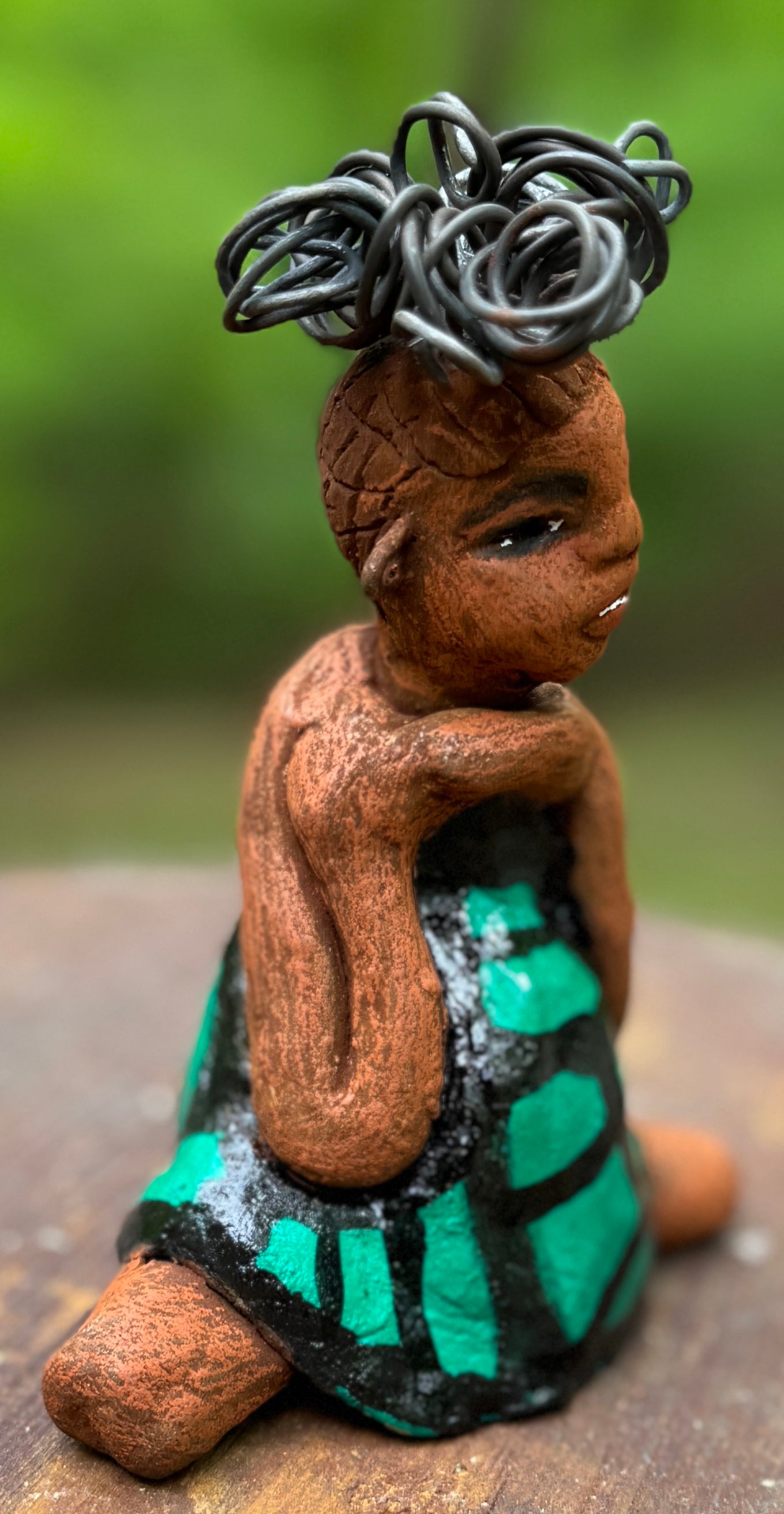 Discover Fayola, the bold figurine standing at 6" x 4” x 3” and weighing only 8.6 ozs, adorned in a striking black and green African print dress. With her hair styled in coils and her hands calmly resting in a yoga pose, Fayola emanates confidence. Join the Herdew Collection and embark on an exciting journey with our complimentary shipping and customer-friendly return policy. Don't hesitate to claim this unique treasure!