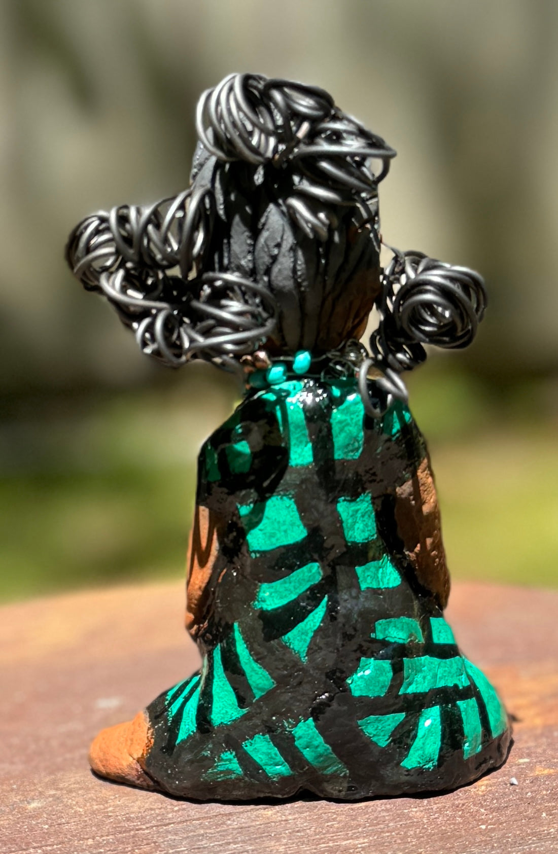 Experience the bold and fearless Traci from the Herdew Collection! This raku fired sculpture stands tall at 6" x 4" x 3" and weighs a brave 10.9 ozs. Clothed in a striking yellow striped green dress, Traci's coiled wire hair stretches over 1 foot. With confident outstretched arms, she strikes a prayerful yoga pose. Begin your collection with the captivating Traci and embrace adventure!