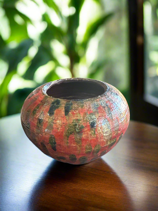 This red and green metallic vase, featuring a spotted design, is 4 inches tall and 6 inches wide. It weighs 1 pound and has a 4-inch opening, making it versatile for all types of flowers. The vase has been expertly crafted using the Raku firing technique for a unique and stunning finish.