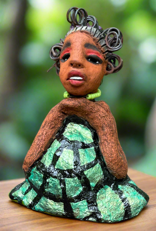 Introducing Mira, the fearless figurine measuring 6.5" x 3.5" x 3" and weighing only 13.5 ozs. Clad in a stunning black and green African print dress, with her coiled hair as her crown, Mira exudes audacity as she confidently rests her hands underneath her head in a yoga pose. Join the Herdew Collection and embark on a journey of excitement with our free shipping and customer-friendly return policy. Don't miss out on this one-of-a-kind treasure!


