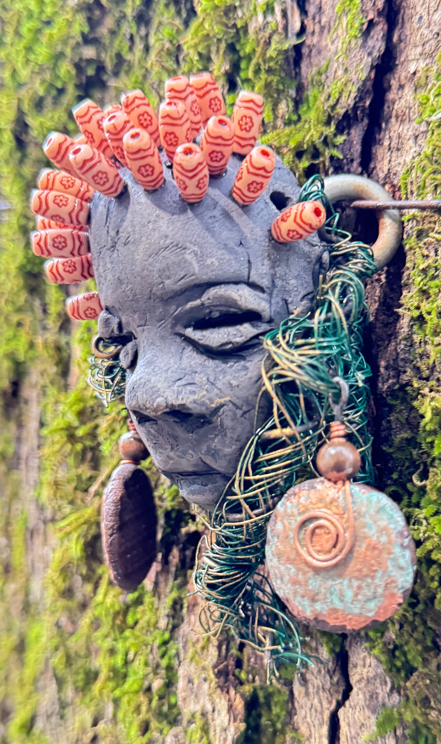 Catto is a 4” x 6” 6oz. mixed media raku fire mask made with 25 feet of 24 and 16 gauge wire. It has a stunning Smokey black complexion and comes with a large Raku fired earring and a wooden bead headdress. This makes Catto a lovely addition to your HerDew mask collection.