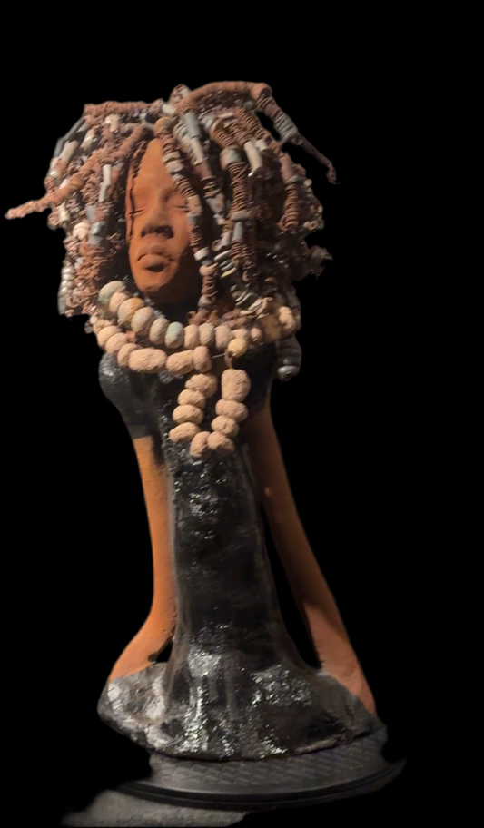 Introducing "Tina," an alluring ceramic artwork created by esteemed artist Lester Jones. Originally showcased at the Chicken & Biscuits play exhibit, this piece portrays a figure with closed eyes and a serene expression, exuding strength, dignity, and cultural pride. Drawing inspiration from the iconic Tina Turner, Lester aptly named this sculpture. The intricate dreadlocks, crafted from glazed and coiled materials, are a stunning representation of traditional and modern artistic fusion. With earthy beads a