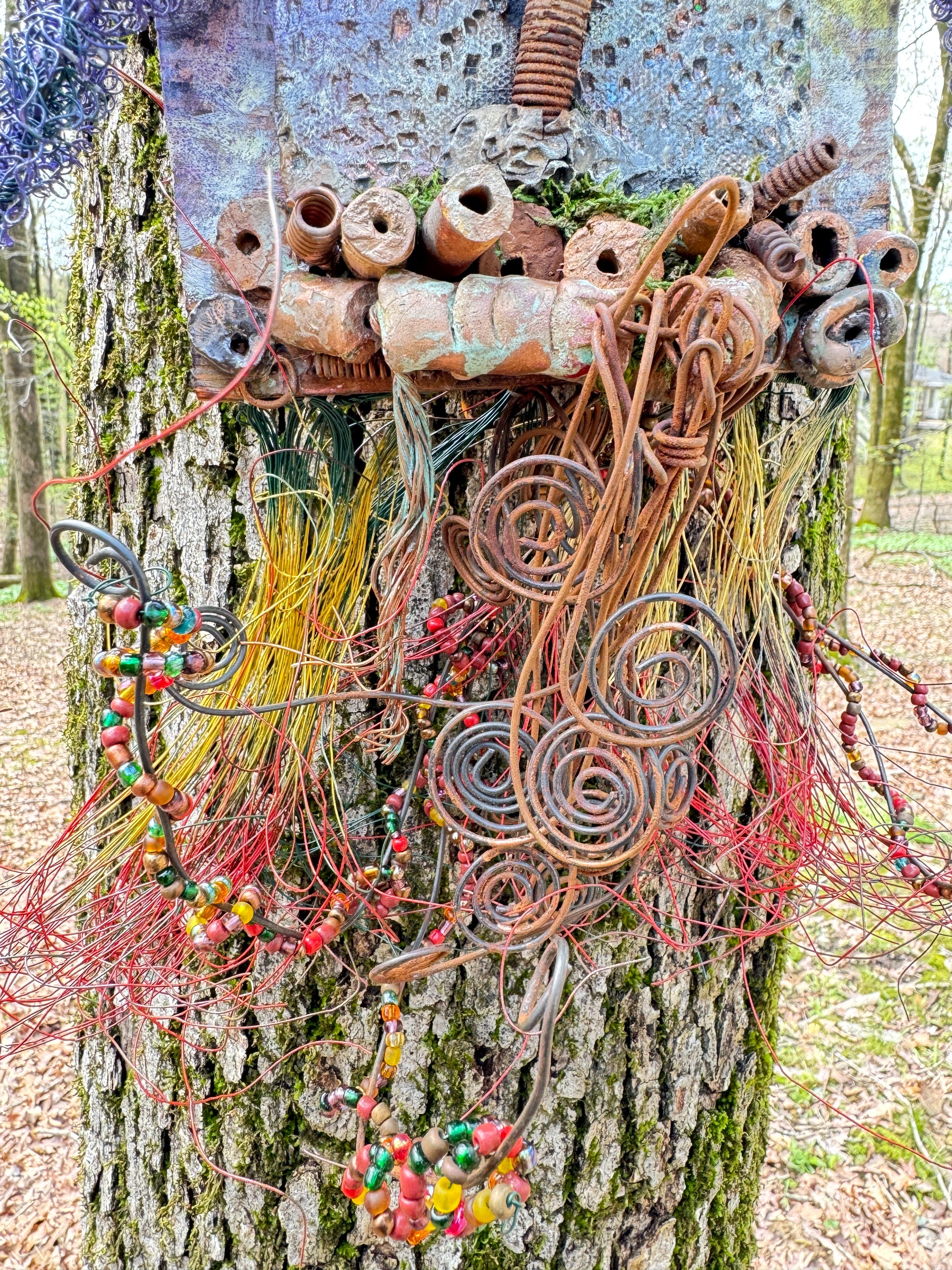 Experience the whimsical world of Purple Dusk with this mixed media landscape. Measuring 20"x16", it combines 16- and 24-gauge wire with handmade Raku fire beads, and even includes a RAKU fired and hand painted texture tile on a 7"x5" wood base. Let the sun peek through the vibrant purple dusk leaves and transport you to a lazy warm summer day.