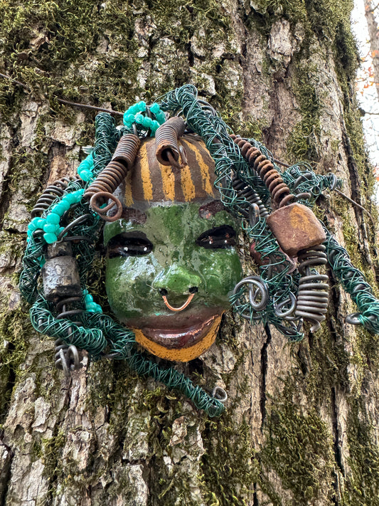 Beverly is a 5" x 6" Raku-fired mask, boasting over 20ft of 16 and 24-gauge wire. Her olive green complexion is decorated with baby blue beads and coils in her green locs for hair. For the holidays, Beverly has been discounted so you can add her as a starter piece to your collection, or gift her as a special treat.