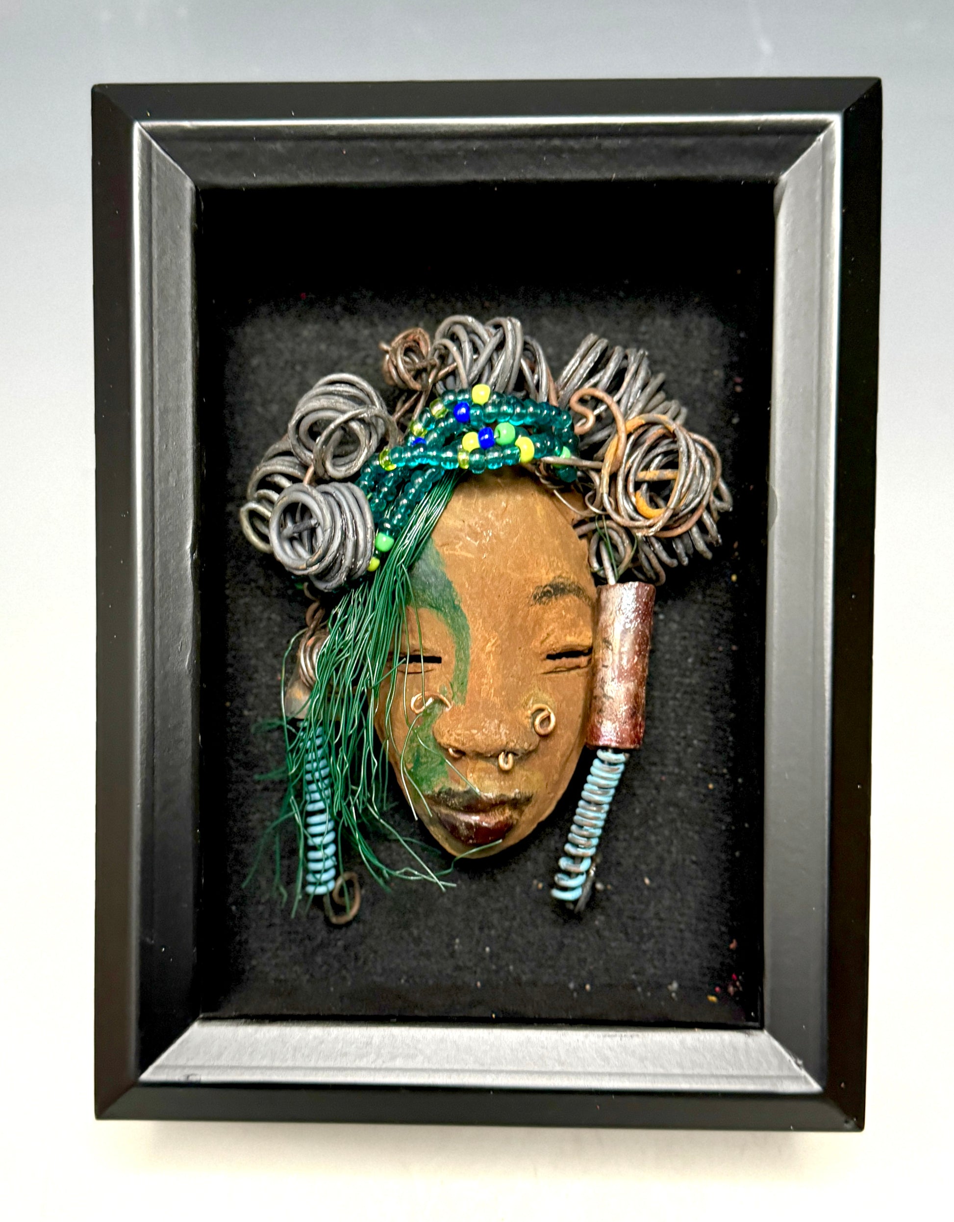 At 5" x 8" in size,  Marcel makes a stunning addition to walls, trees, and shadow boxes. His signature brown and amber braided hair is ornamented with handcrafted Raku beads, while his skin has a warm honey brown hue. Each piece is equipped with over 10 16 & 24-gauge wire in the hair. This fashionable sculpture will bring a modern flair to any room - simply place it in a shadow box and enjoy!