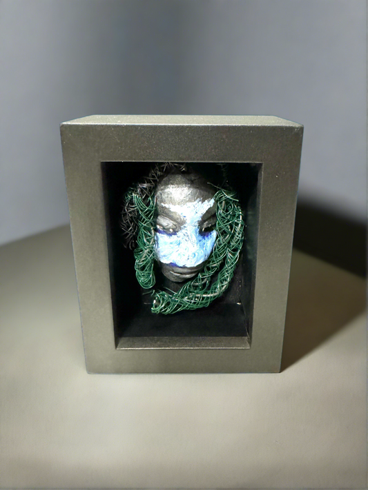 Chandon is a raku fired mask .He is enclosed in a 4“ x 4“ glass covered black shadowbox. He has over 40 feet of 16 and 24 gauge wire as hair. Make a bold statement with this striking mask! Enclosed in a sleek glass shadowbox, Chandon features a unique raku firing technique that makes each creation one-of-a-kind. The wire "hair" extends over 40 feet in length, representing a spirit that is free to explore and take risks. Bring a touch of adventure into your home with this handcrafted piece.